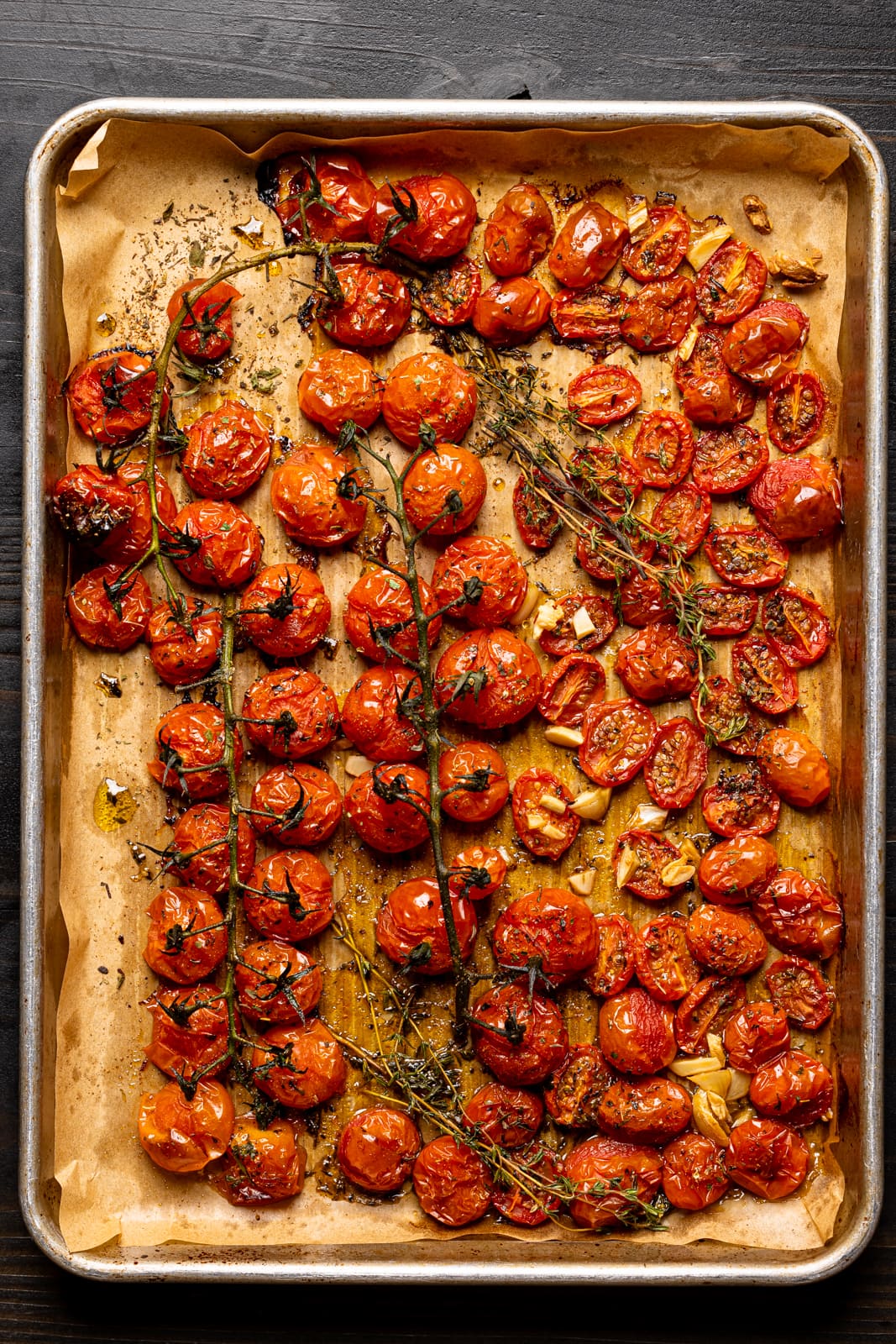 Roasted tomatoes on a baking sheet lined with parchment paper.