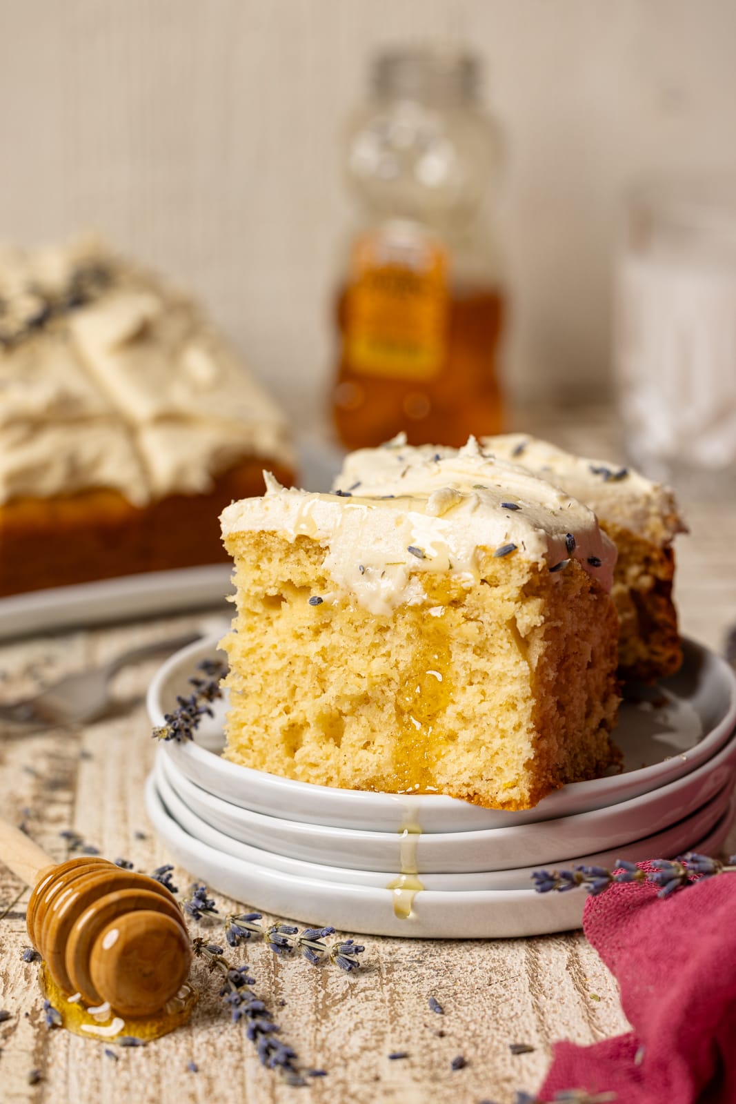 Slice of cake on a stack of plates with honey.