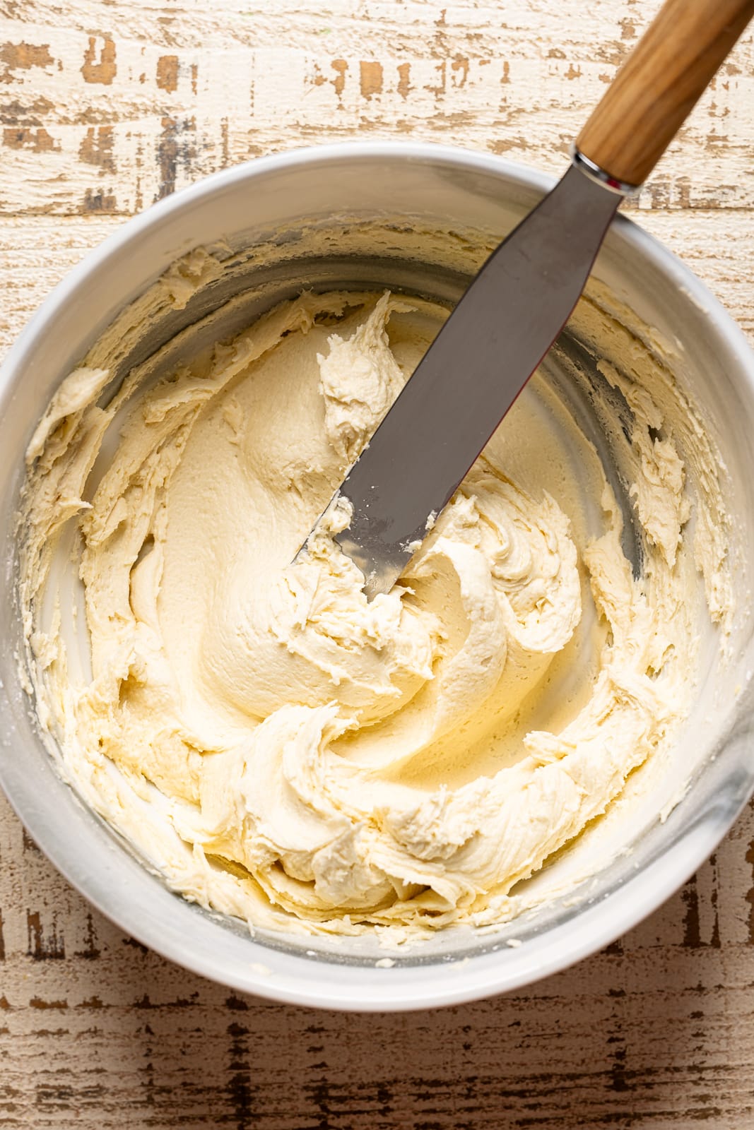 Cake frosting in a bowl with a spatula. 