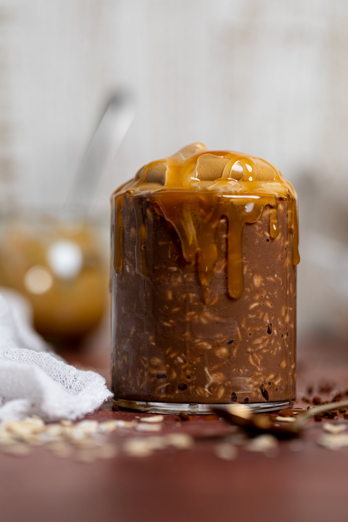 Caramel dripping down the side of a glass of Caramel Mocha Overnight Oats with Whipped Coffee.