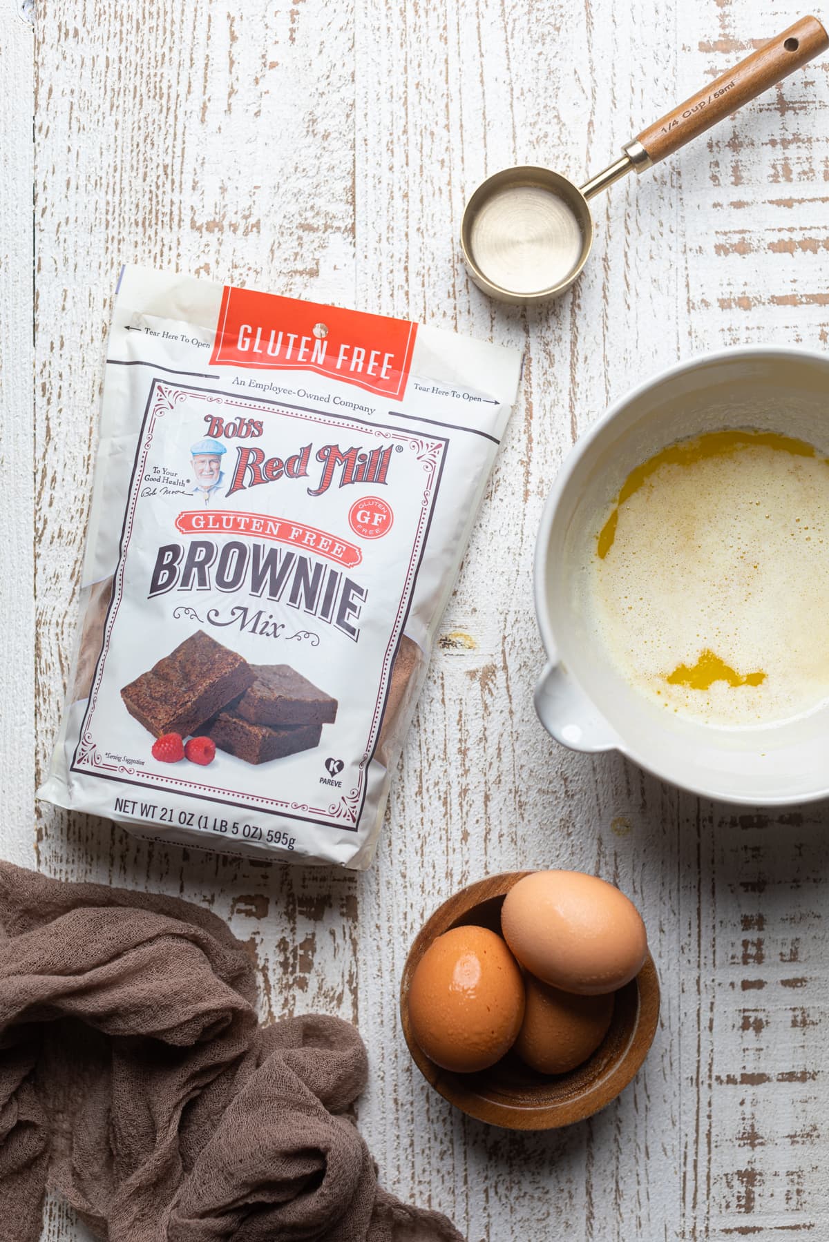 Ingredients for Brownie Cheesecake including gluten-free brownie mix, eggs, and melted butter