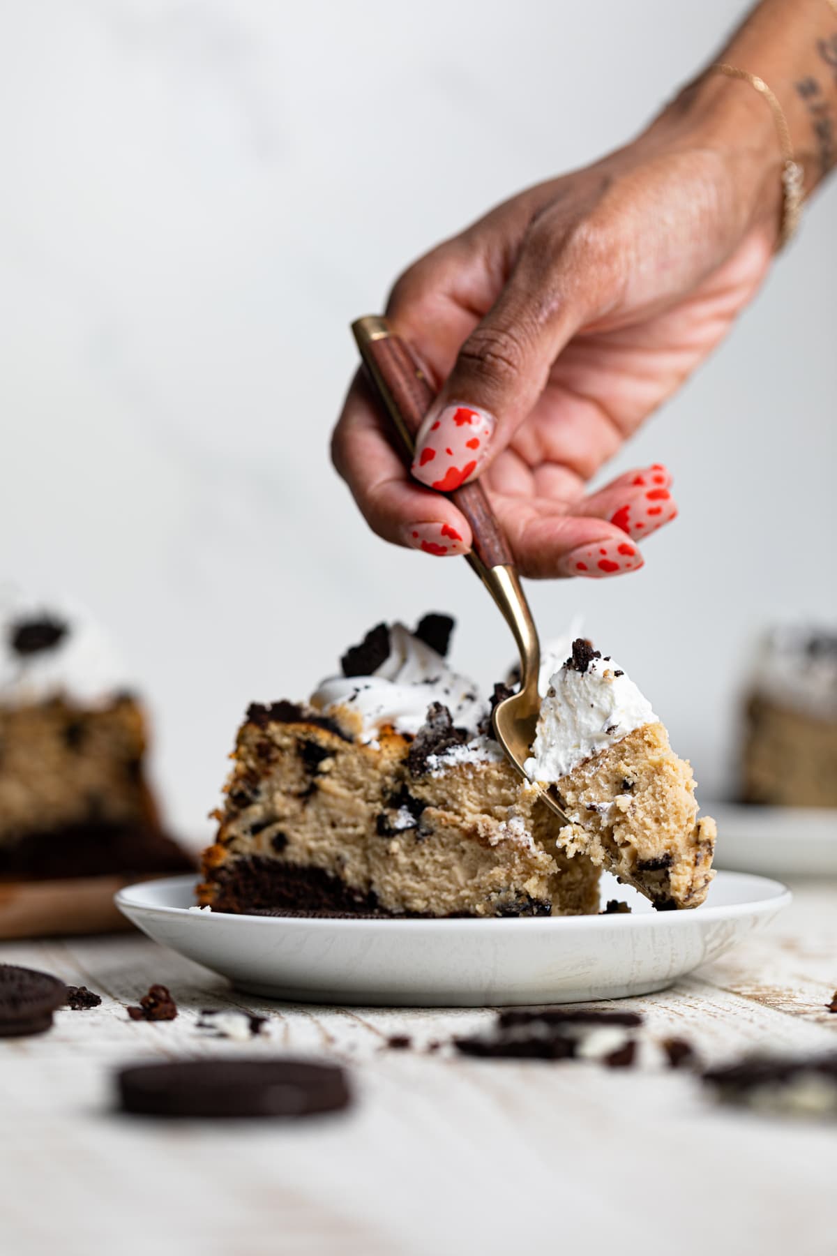 Hand using a fork to grab some Gluten-Free Peanut Butter Cookies N\' Cream Brownie Cheesecake