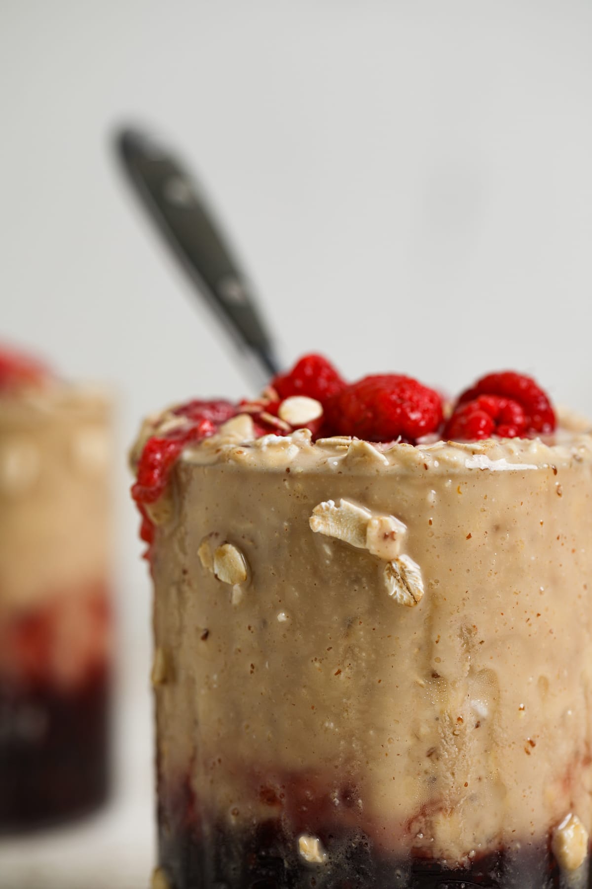 Spoon in a glass of Protein Peanut Butter and Jelly Overnight Oats.