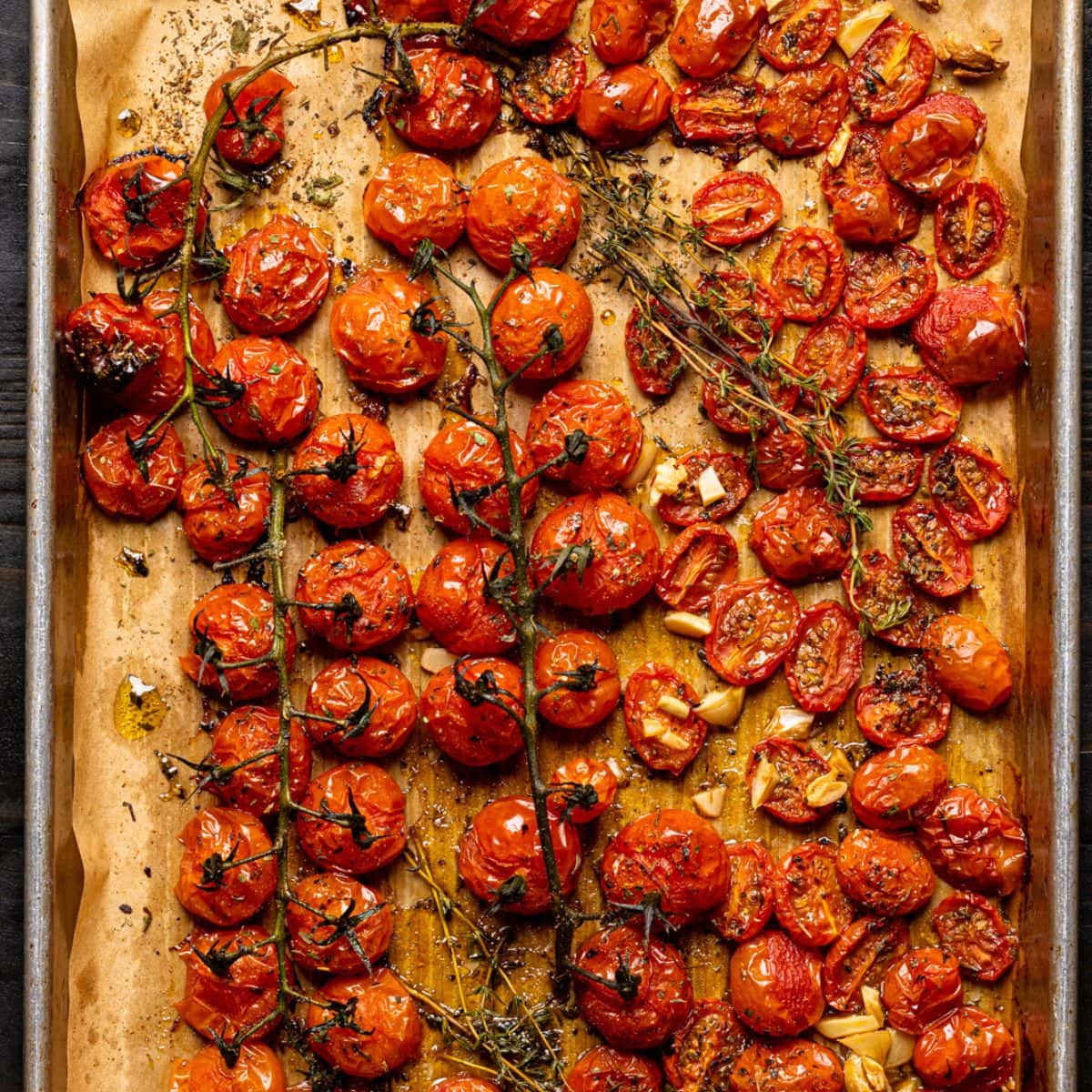 Roasted tomatoes on a baking sheet lined with parchment paper.