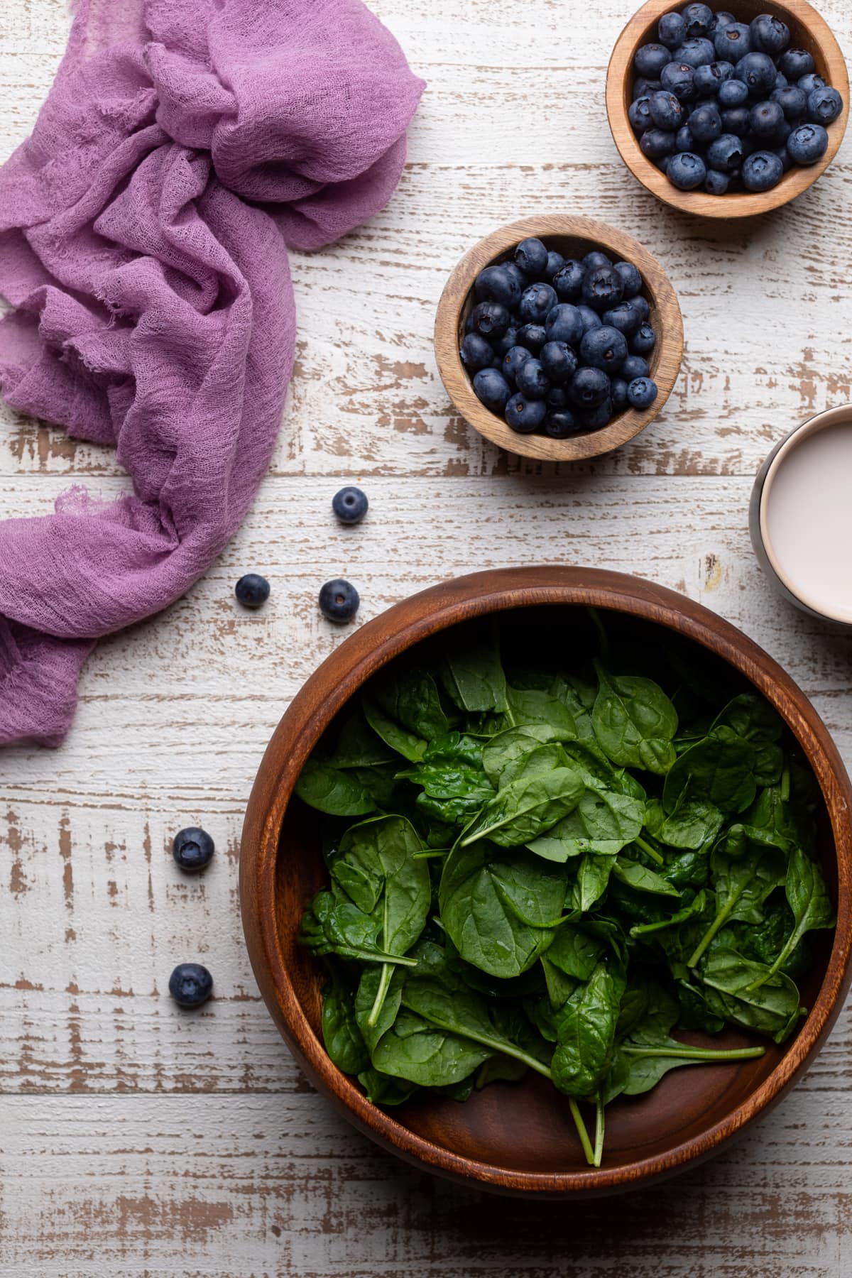 Bowls of almond milk, blueberries, and spinach