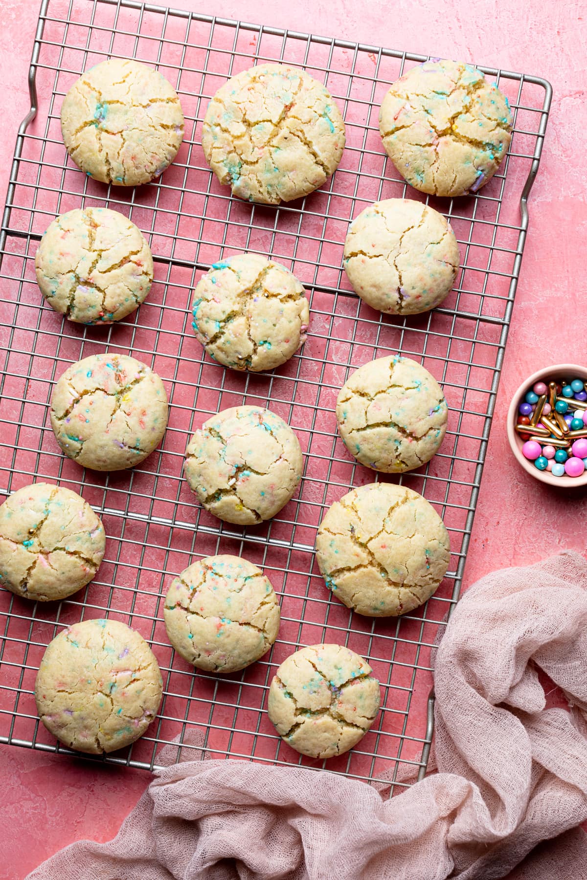 Thick and Chewy Funfetti Cookies on a wire rack next to a small bowl of sprinkles