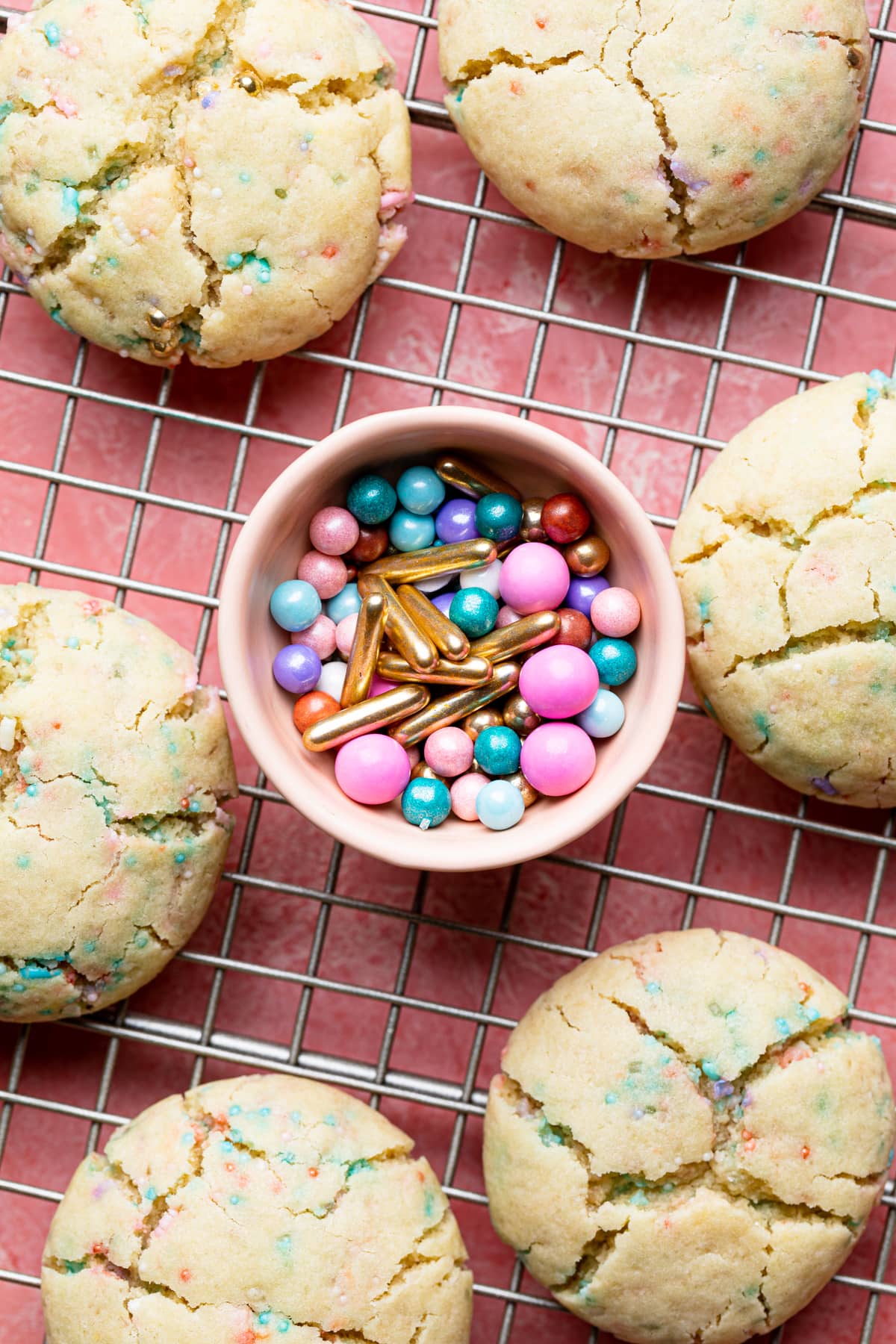 Small bowl of sprinkles among Funfetti cookies on a wire rack