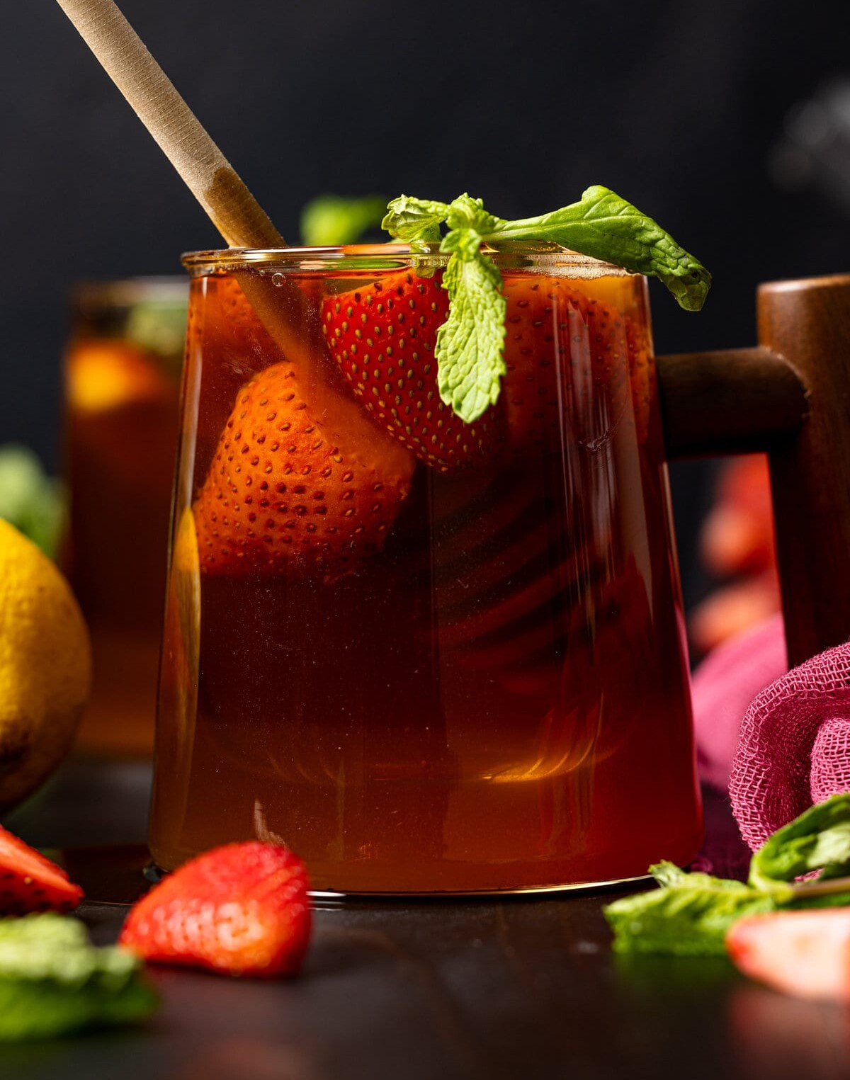 Closeup of a glass with a wooden handle filled with Roasted Dandelion Strawberry Tea