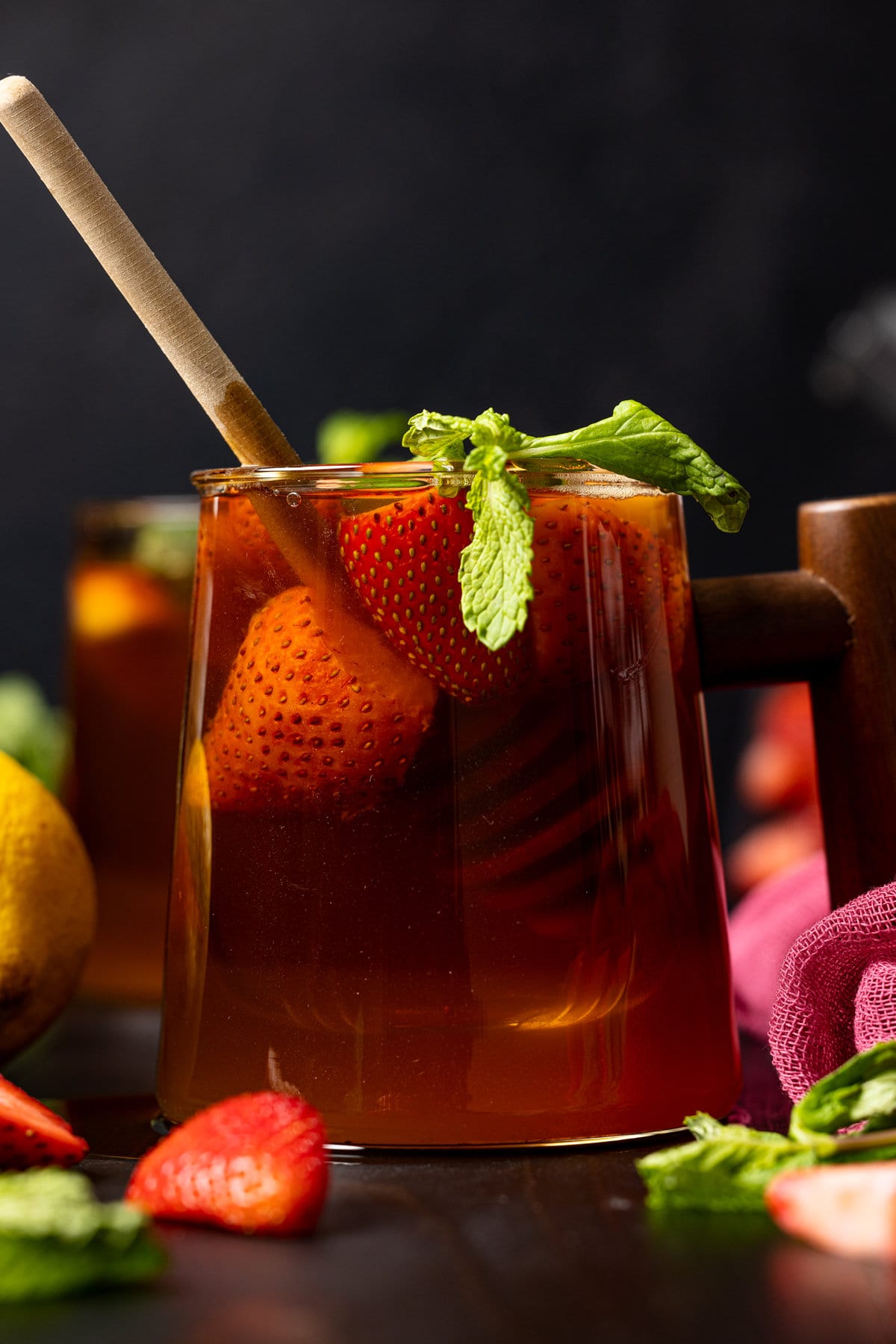 Closeup of a glass with a wooden handle filled with Roasted Dandelion Strawberry Tea