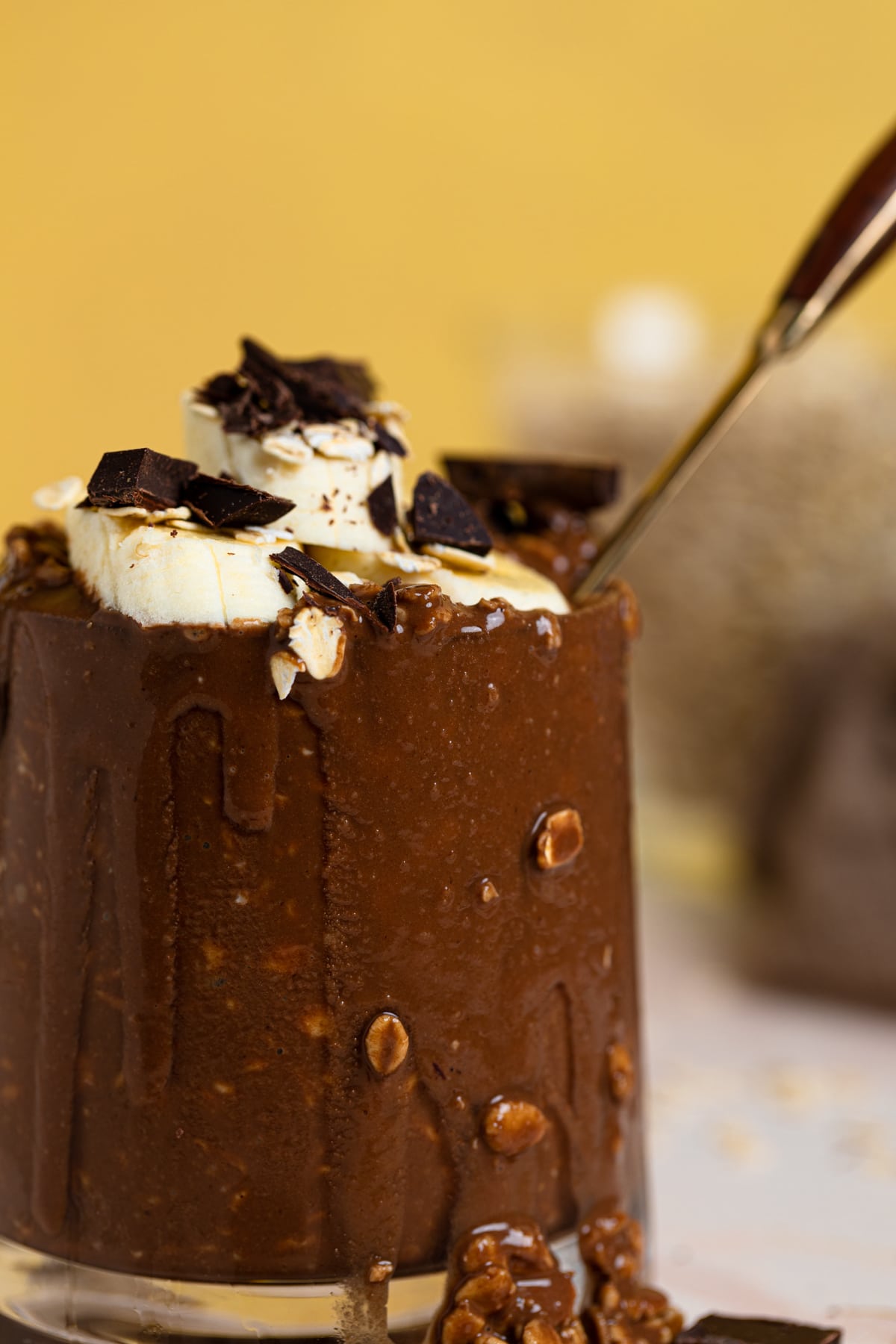 Spoon in overflowing glass of Triple Chocolate Protein Overnight Oats.