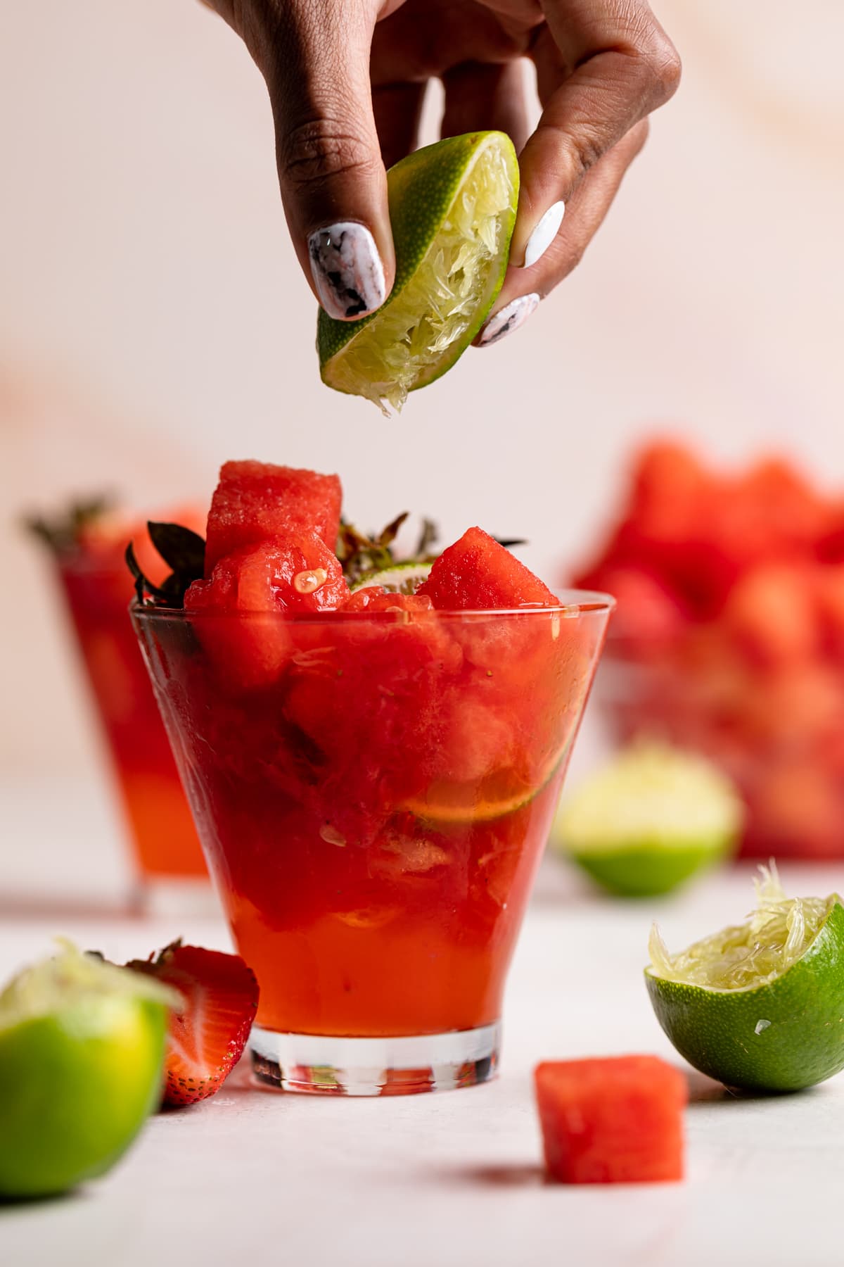 Watermelon Strawberry Lime Mocktail with a hand squeezing lime juice in.