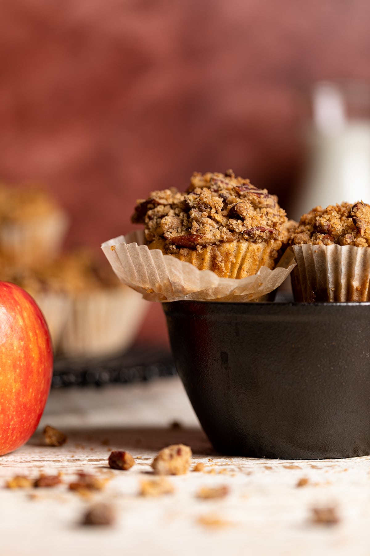 Vegan Apple Spice Muffin in a black bowl with the muffin liner partially peeled off