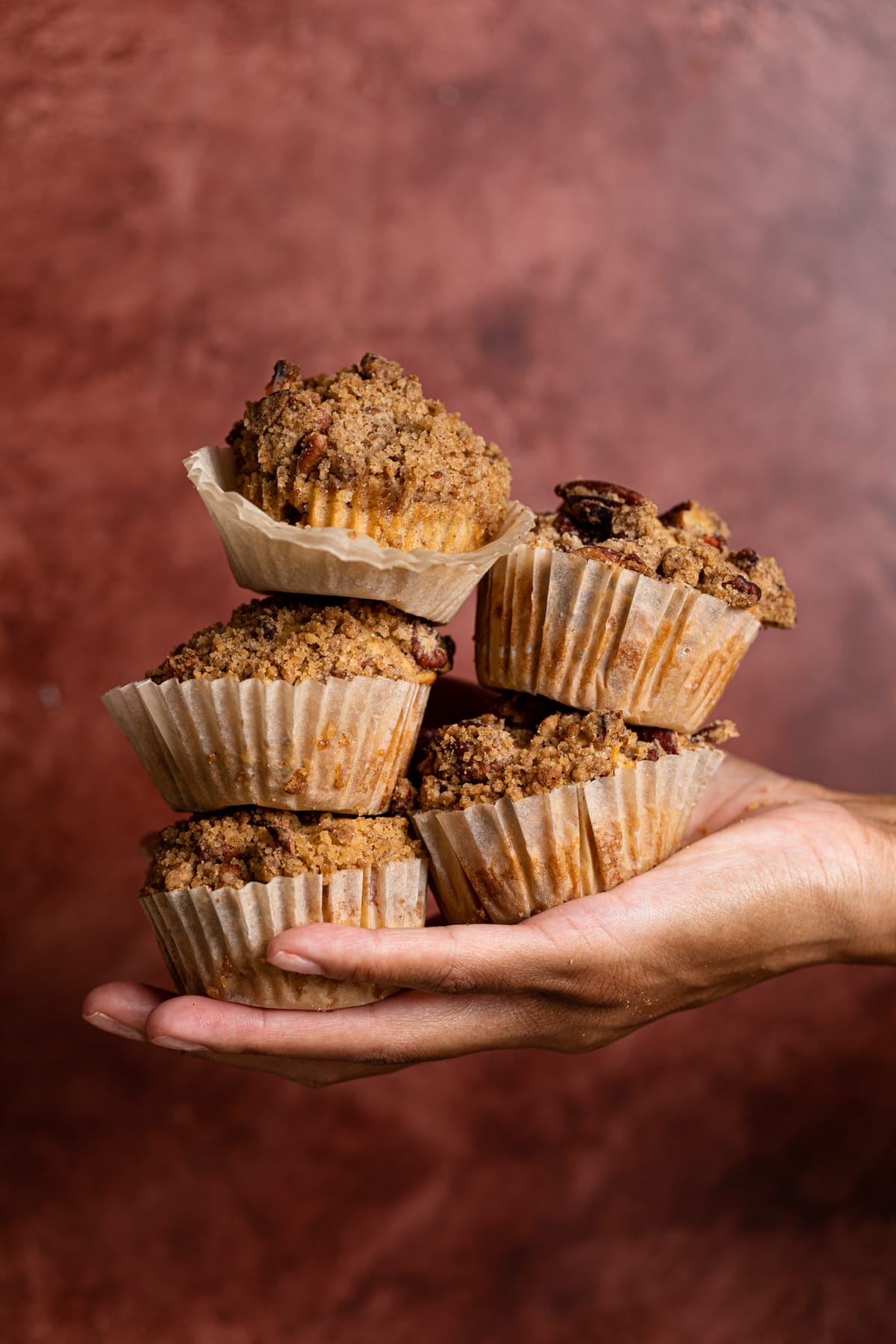 Hand holding five Vegan Apple Spice Muffins 