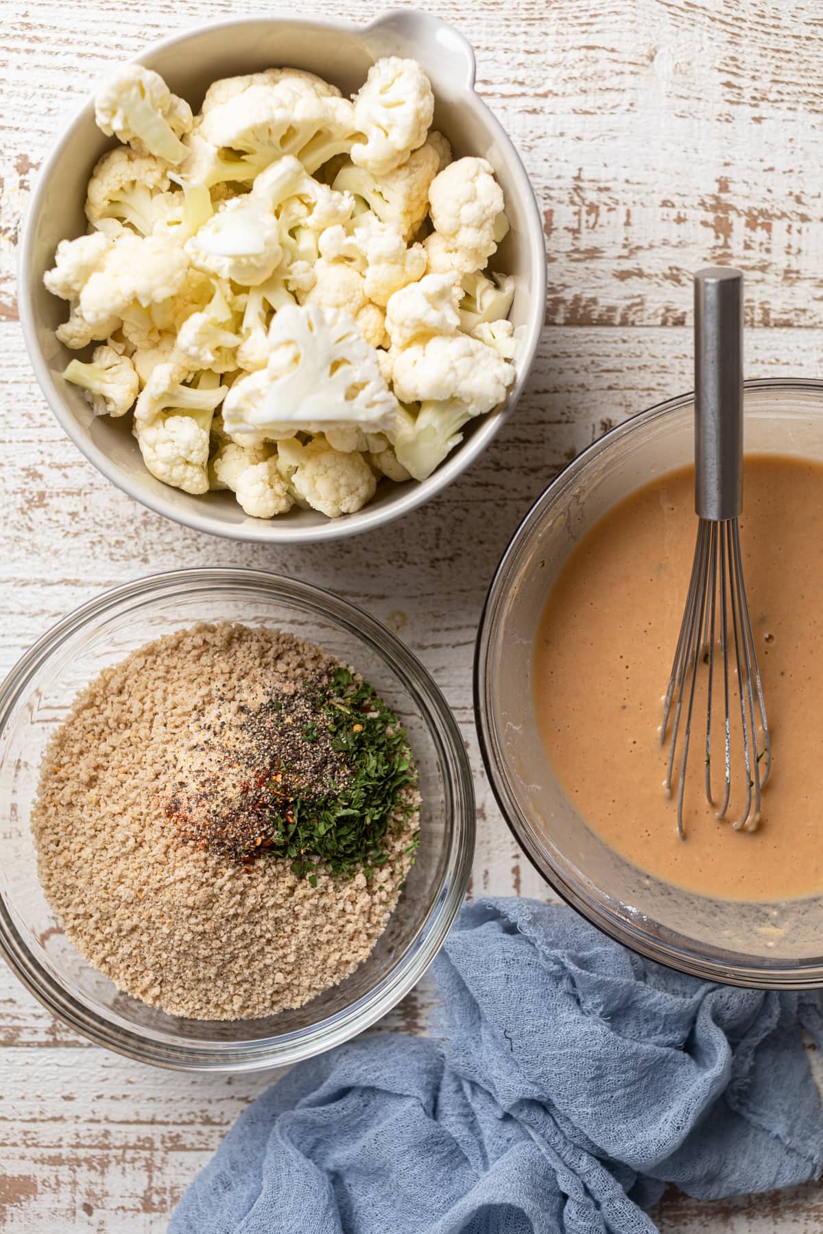 Bowls of chopped cauliflower, whisked batter, and bread crumbs