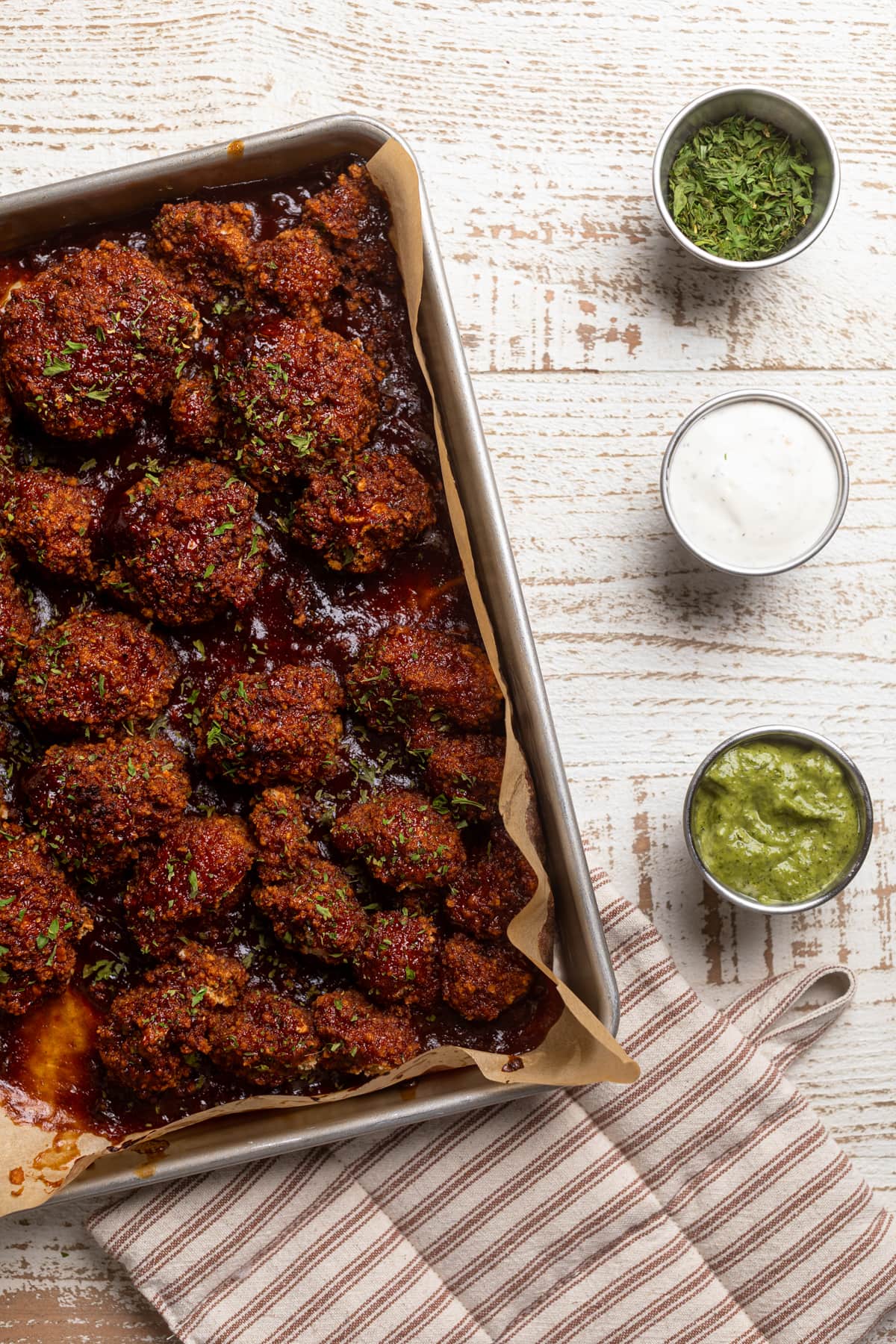 Baking sheet of barbeque Cauliflower Wings next to small bowls of dip