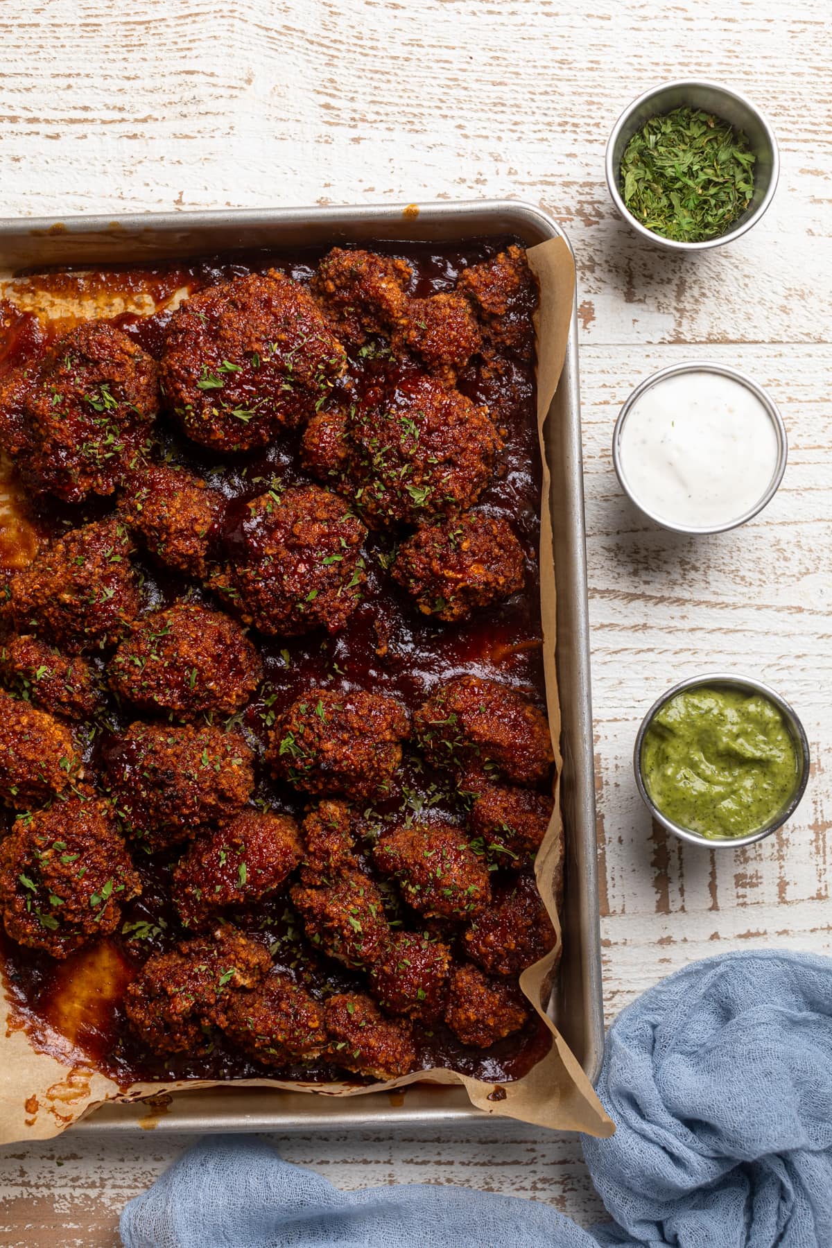 Baking sheet of barbeque Cauliflower Wings next to small bowls of dip