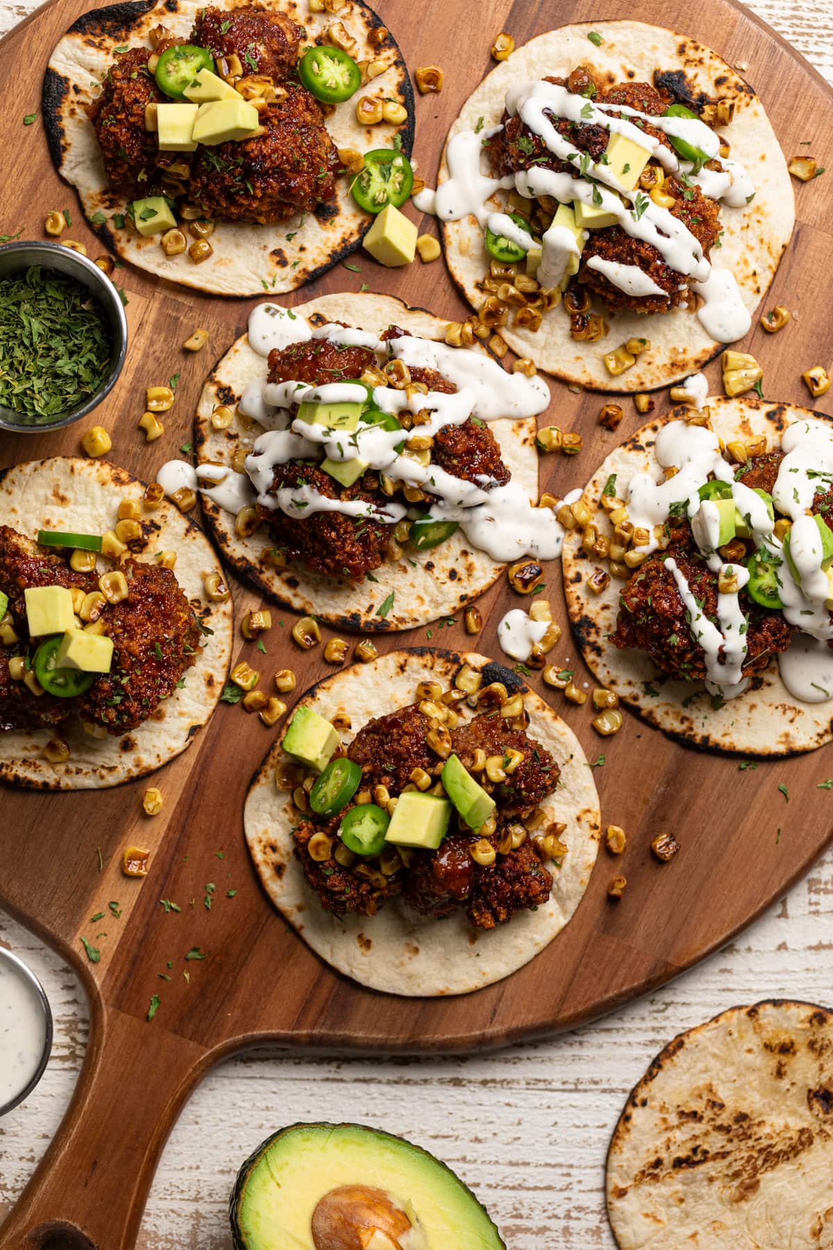 Barbeque Cauliflower Tacos drizzled with white dressing and on a wooden board