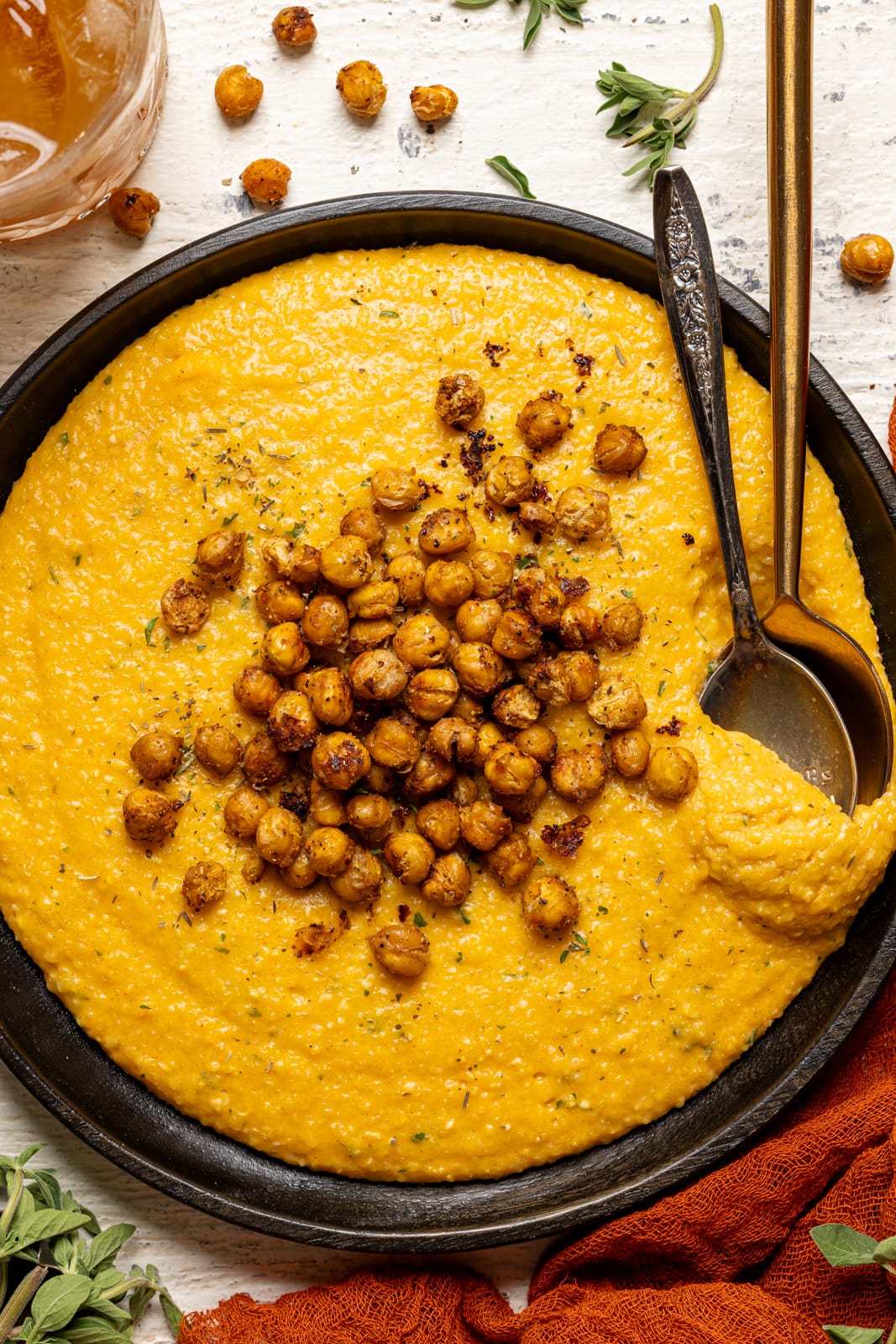 Chickpeas and grits on a black plate with two spoons.