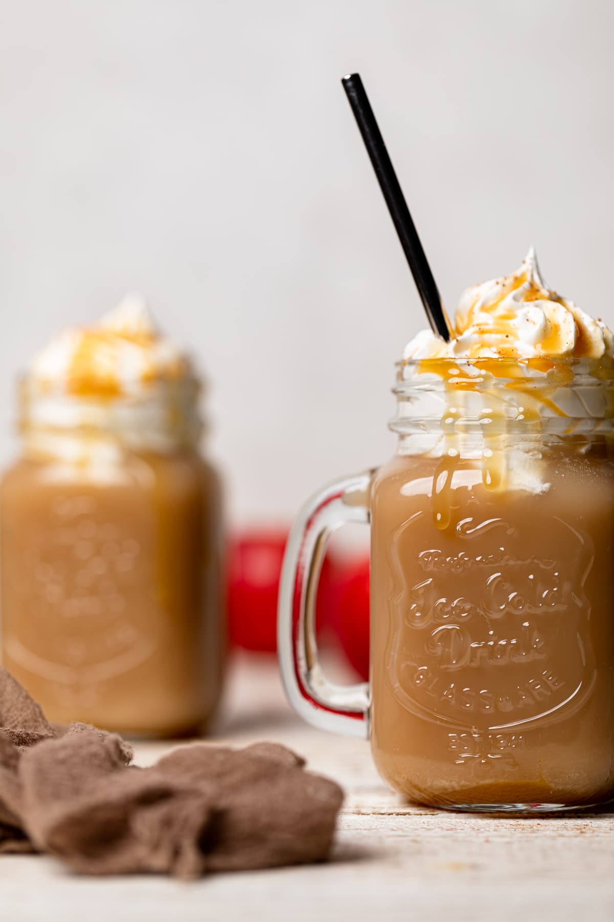 Caramel Apple Cider Drink topped with coconut whipped cream and caramel and with a metal straw