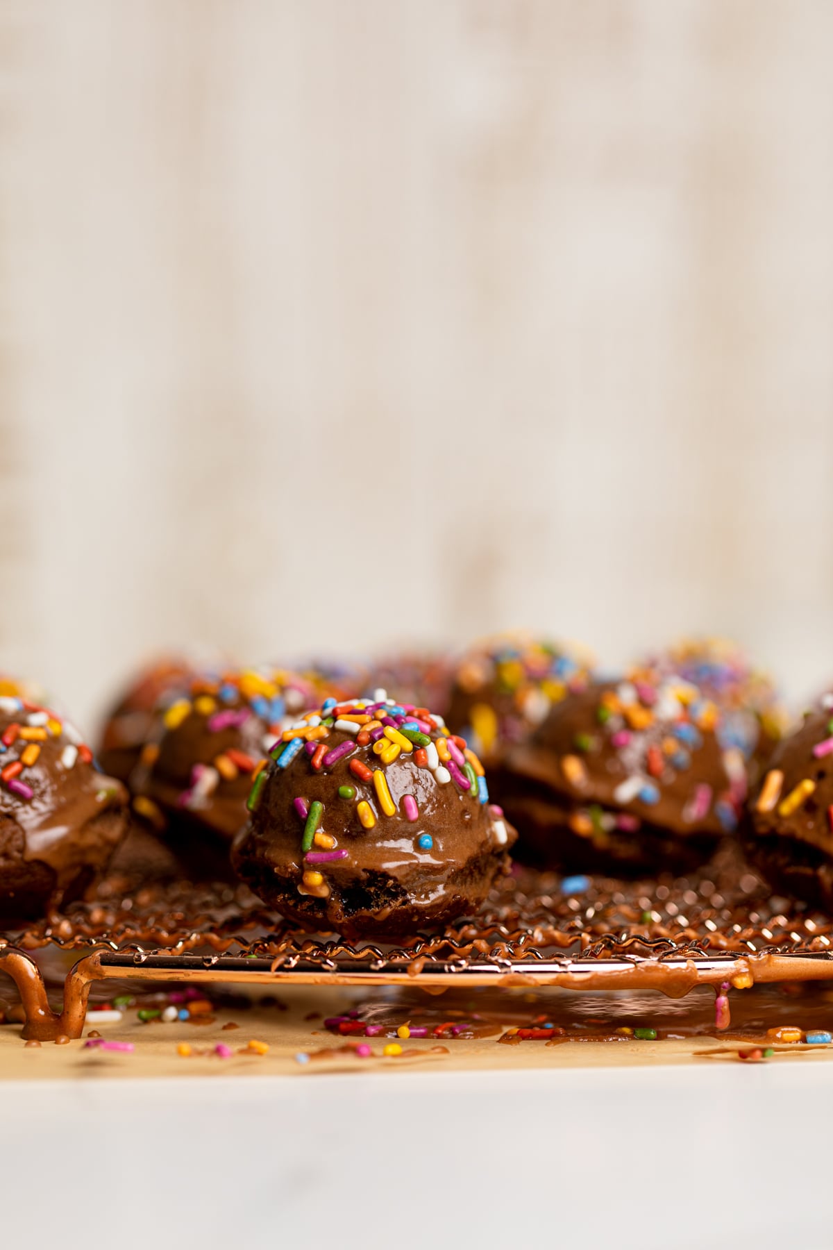 Side view of Vegan Chocolate Donut Holes on a wire rack