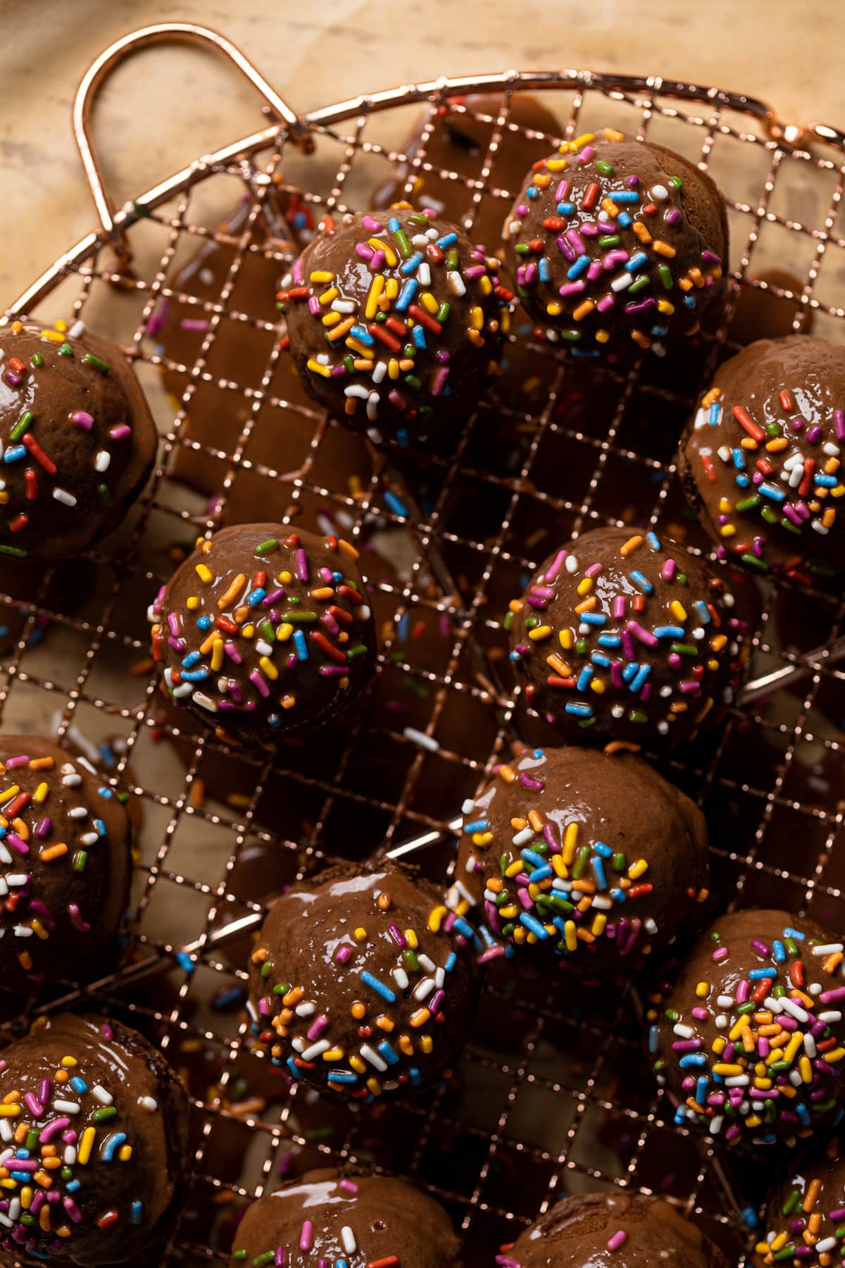 Vegan Chocolate Donut Holes topped with sprinkles and on a wire rack