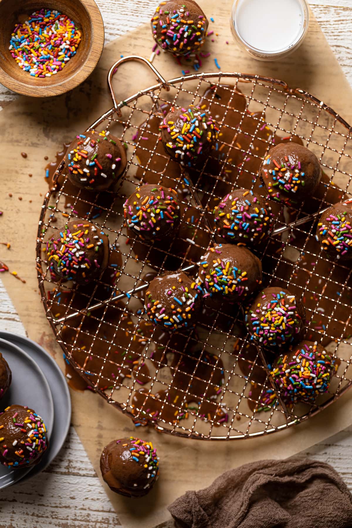 Vegan Chocolate Donut Holes topped with sprinkles on a wire rack