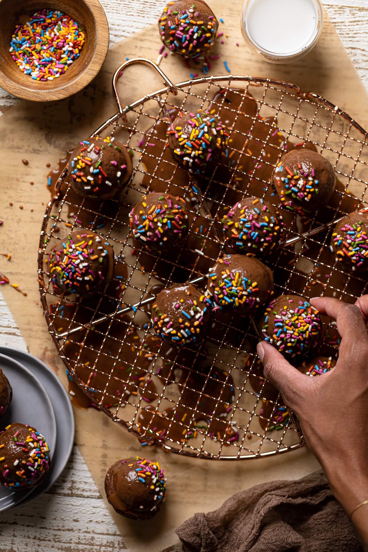 Hand grabbing a Vegan Chocolate Donut Hole from a wire rack