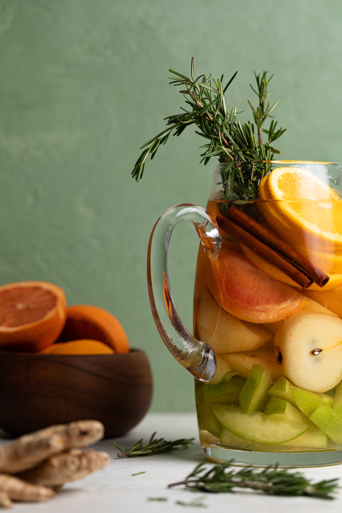 Citrus Ginger Pear Detox Infused Water in a pitcher with herbs.