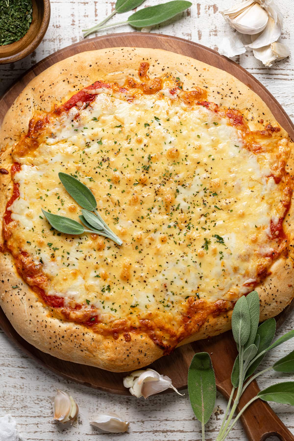 Unsliced Garlic Herb Cheese Pizza on a wooden board