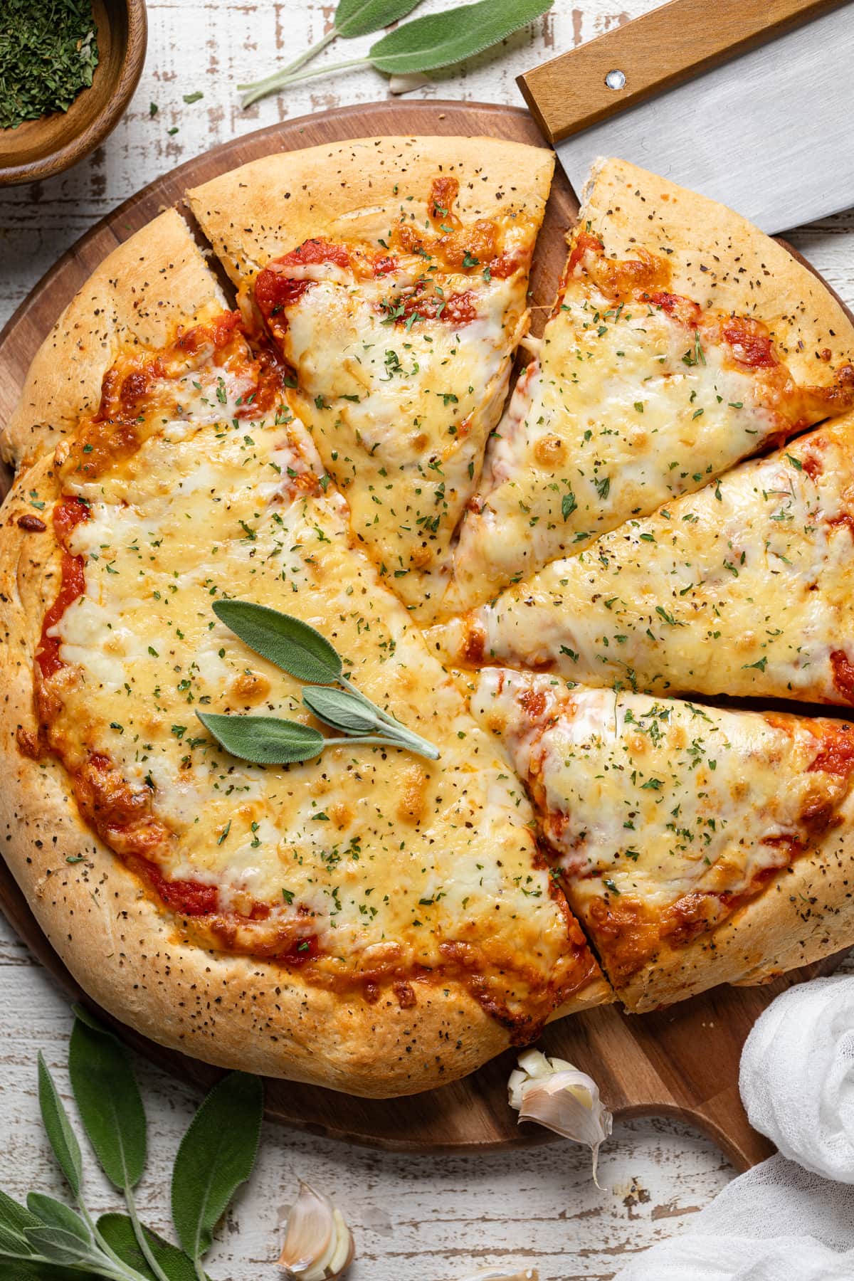 Half-sliced Garlic Herb Cheese Pizza on a wooden board