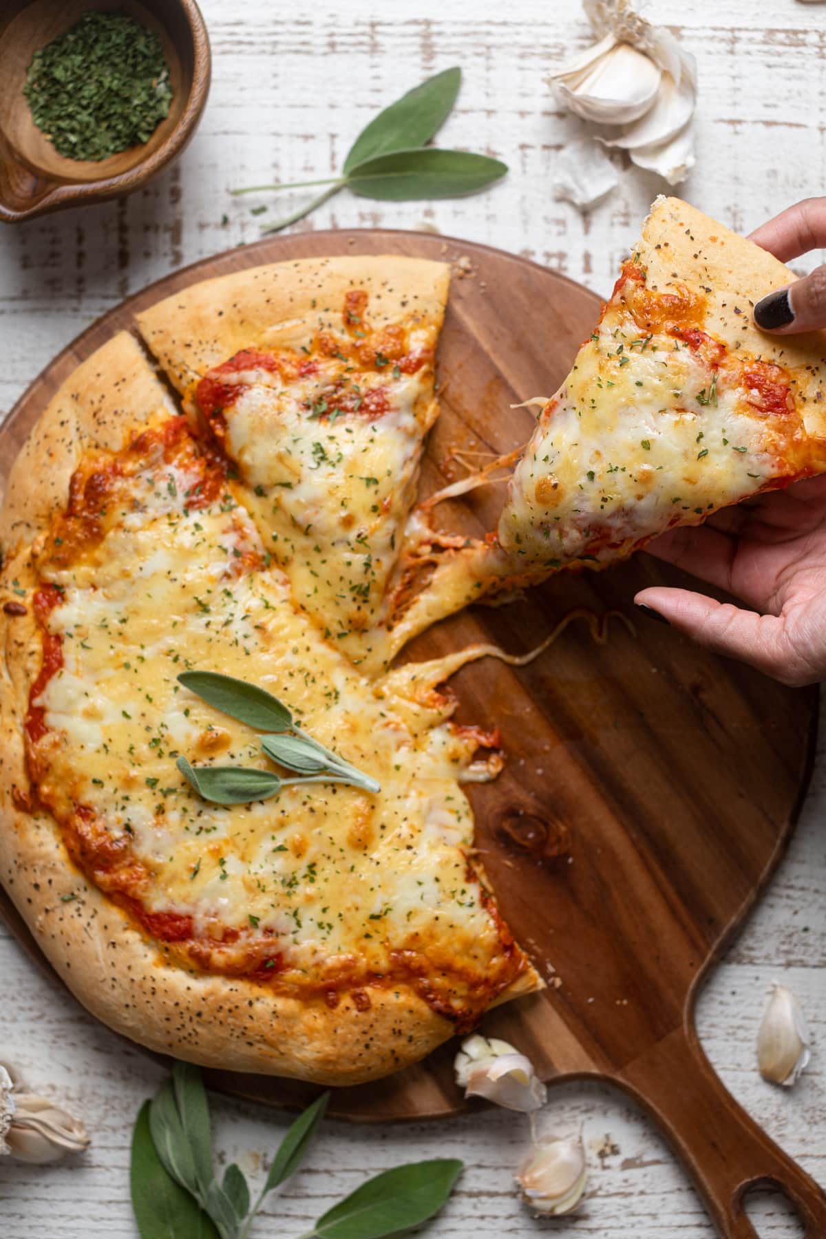 Hand grabbing a slice of Garlic Herb Cheese Pizza 