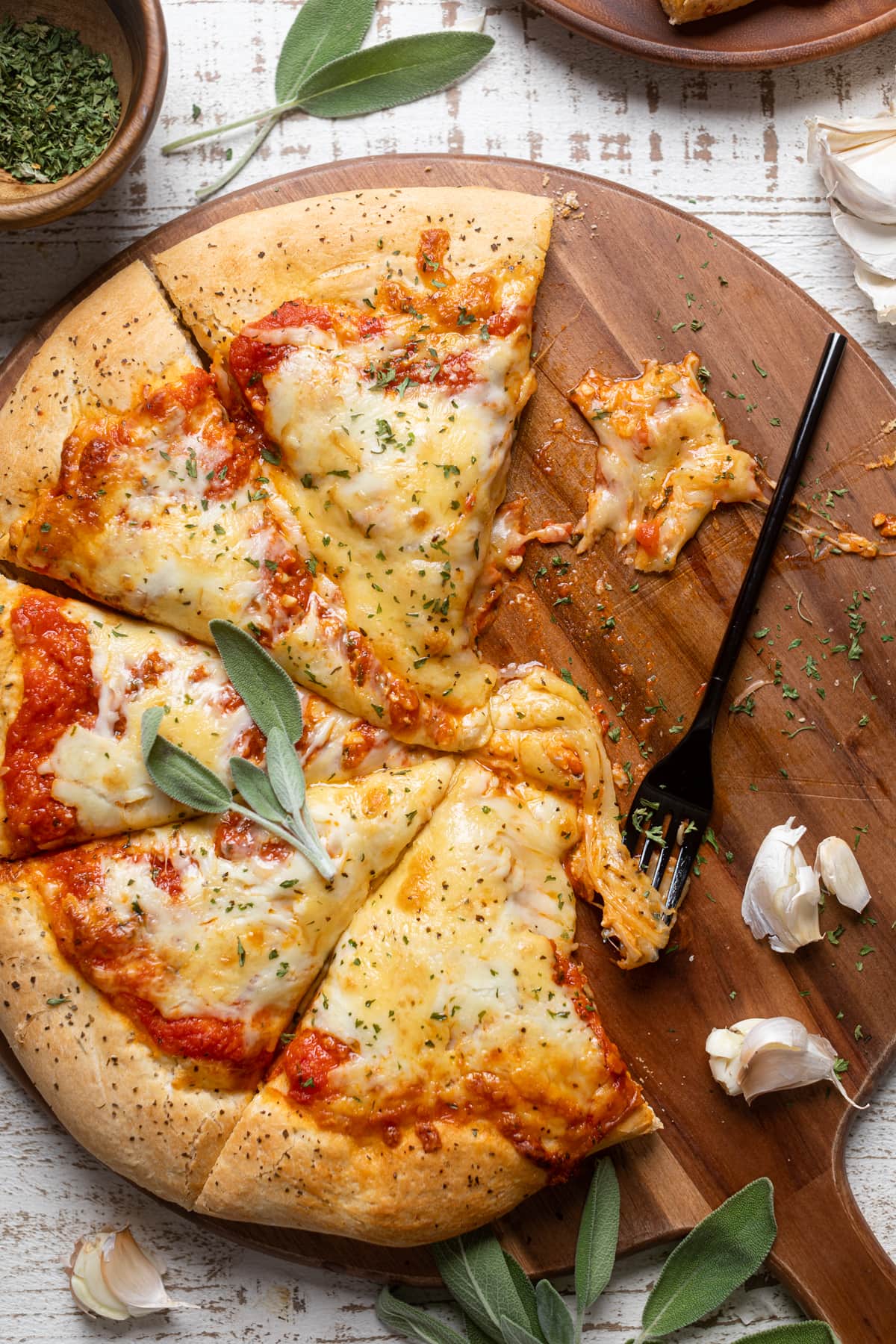 Partially-served Garlic Herb Cheese Pizza on a wooden board