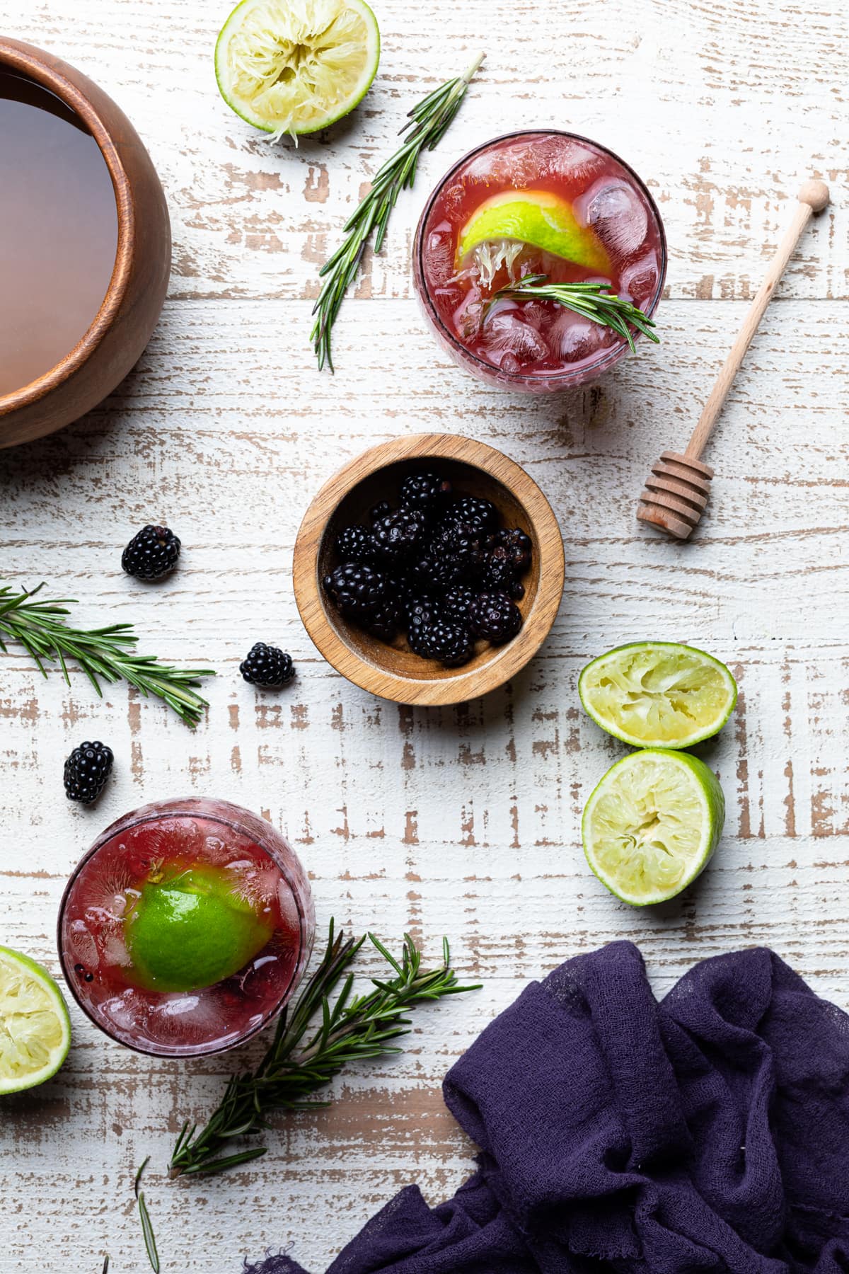 Wooden bowl of blackberries between two Blackberry Lime Mocktails