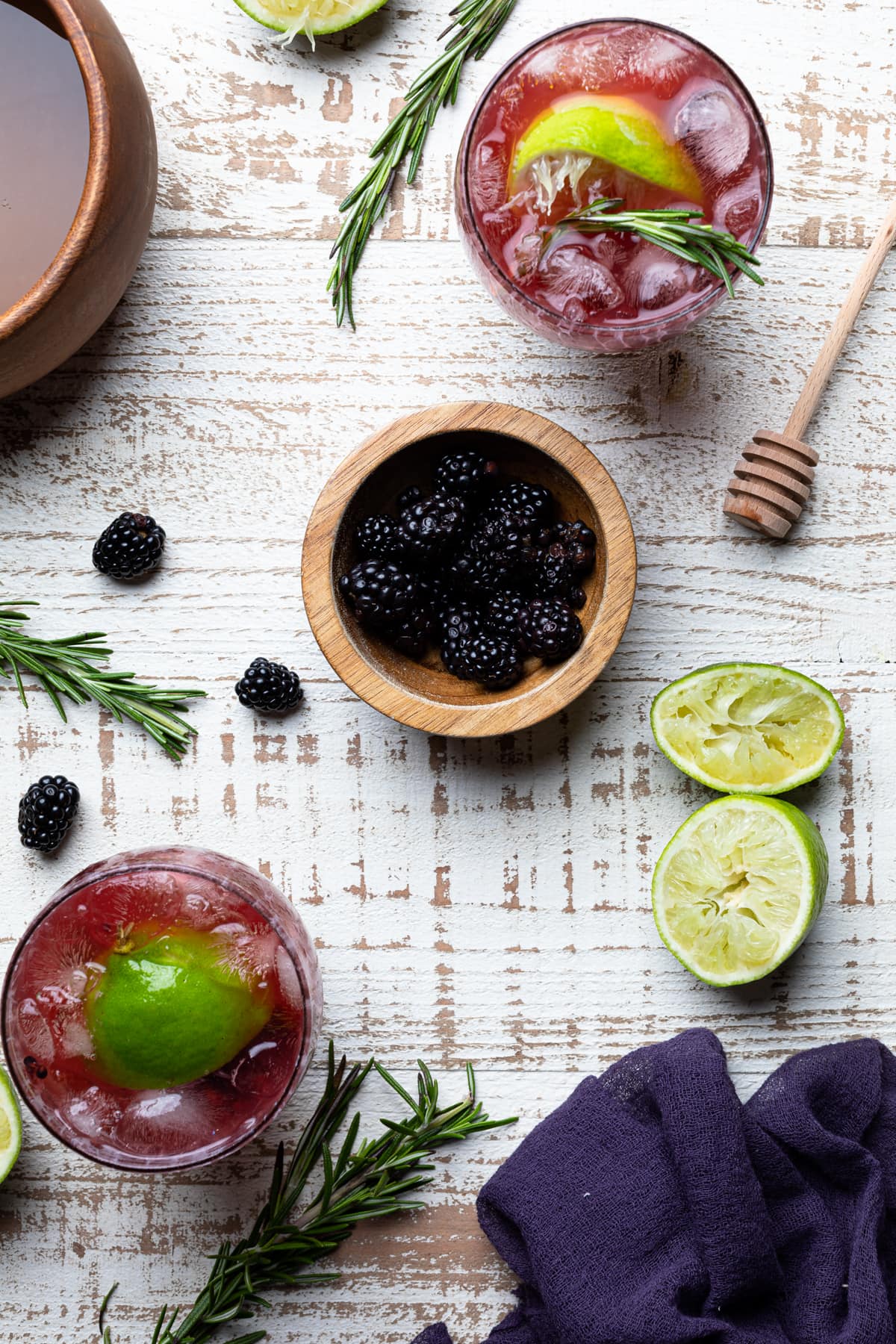 Wooden bowl of blackberries between two Blackberry Lime Mocktails