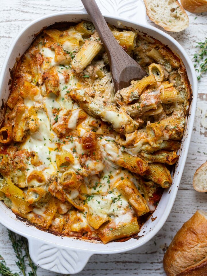 Wooden spoon scooping from Pesto Pasta with Ricotta out of a baking dish