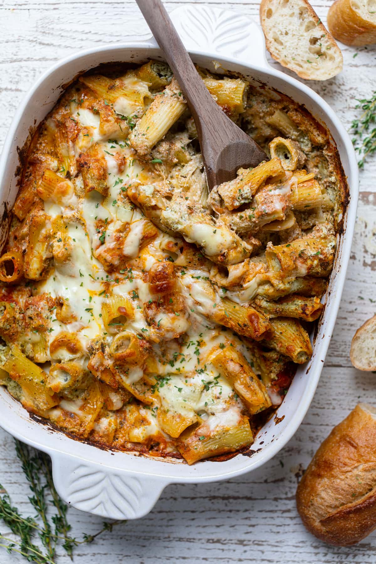 Wooden spoon scooping from Pesto Pasta with Ricotta out of a baking dish