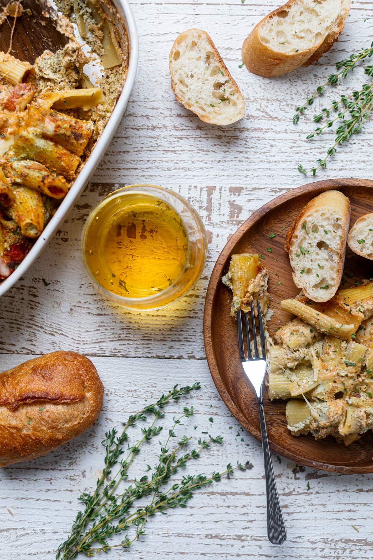 Pesto Pasta on a wooden plate with bread and a fork