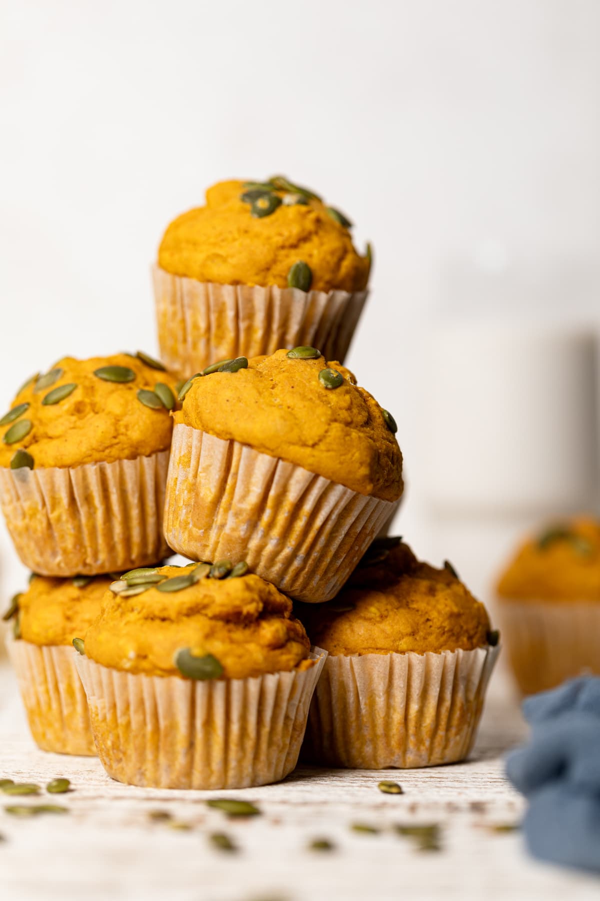 Pile of Vegan Pumpkin Spice Muffins topped with pumpkin seeds