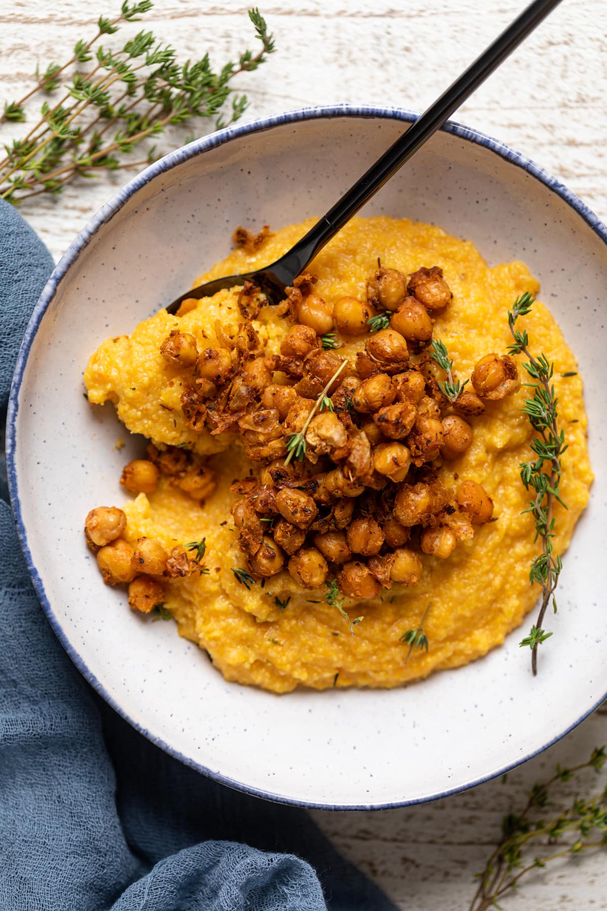 Spoon scooping some Cajun Sweet Potato Grits with Crispy Chickpeas from a bowl