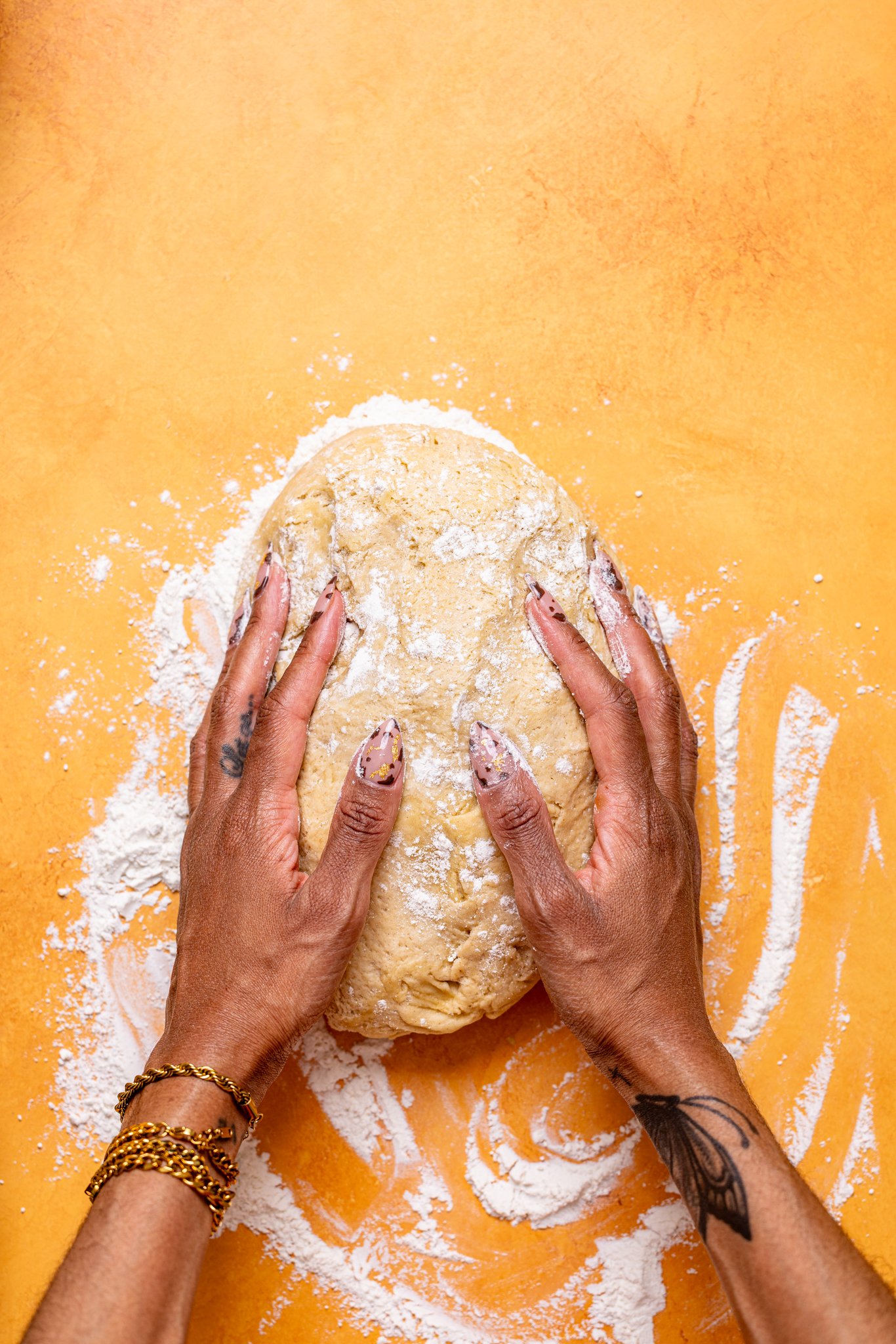 Woman hands atop cinnamon roll dough on a floured table.