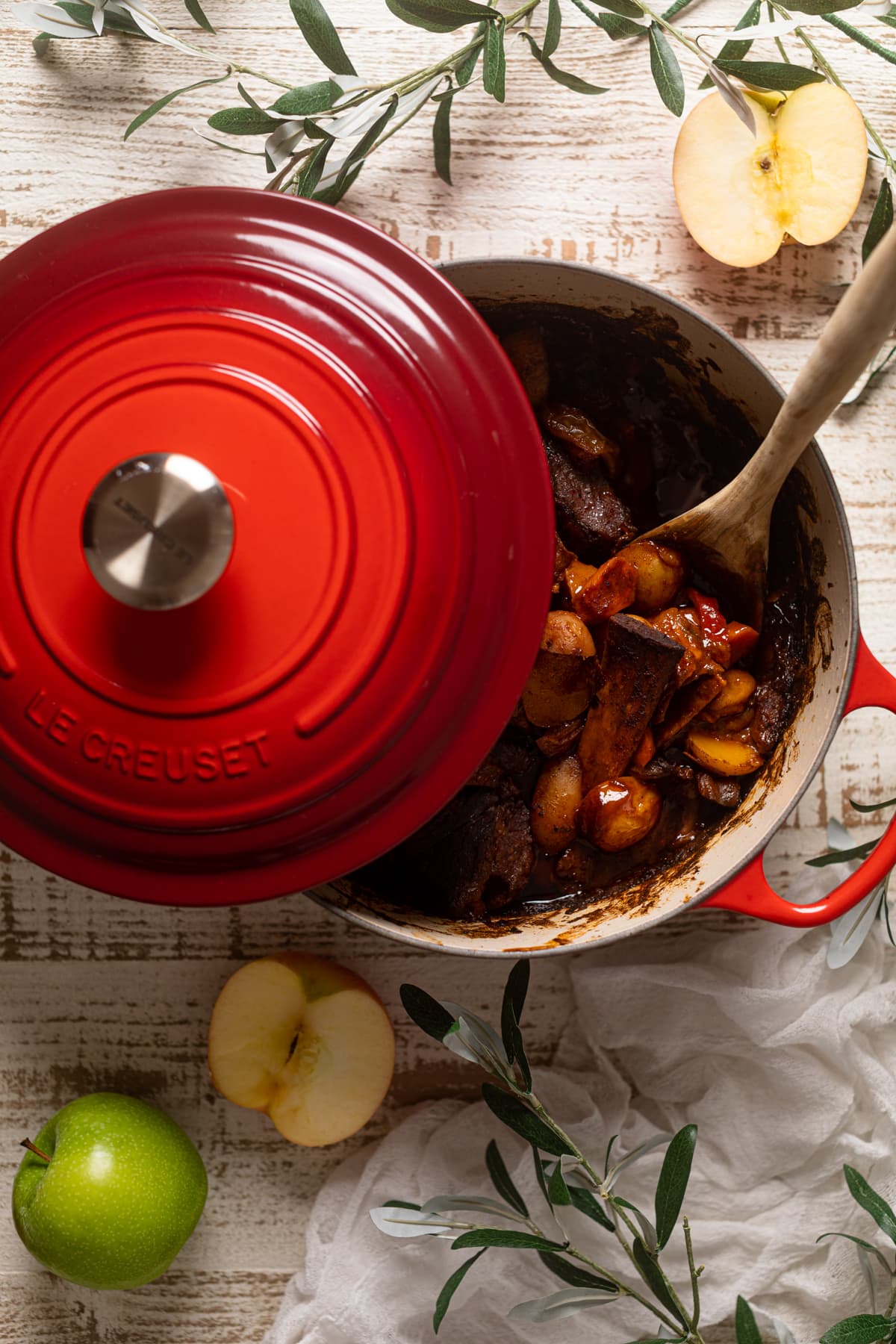 Braised Apple barbeque Ribs and Potatoes in a red Le Creuset Dutch oven with the lid half on