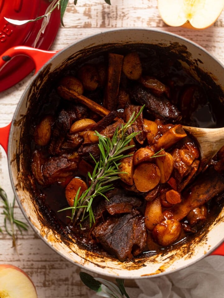Wooden spoon stirring a pan of Braised Apple barbeque Ribs with Potatoes