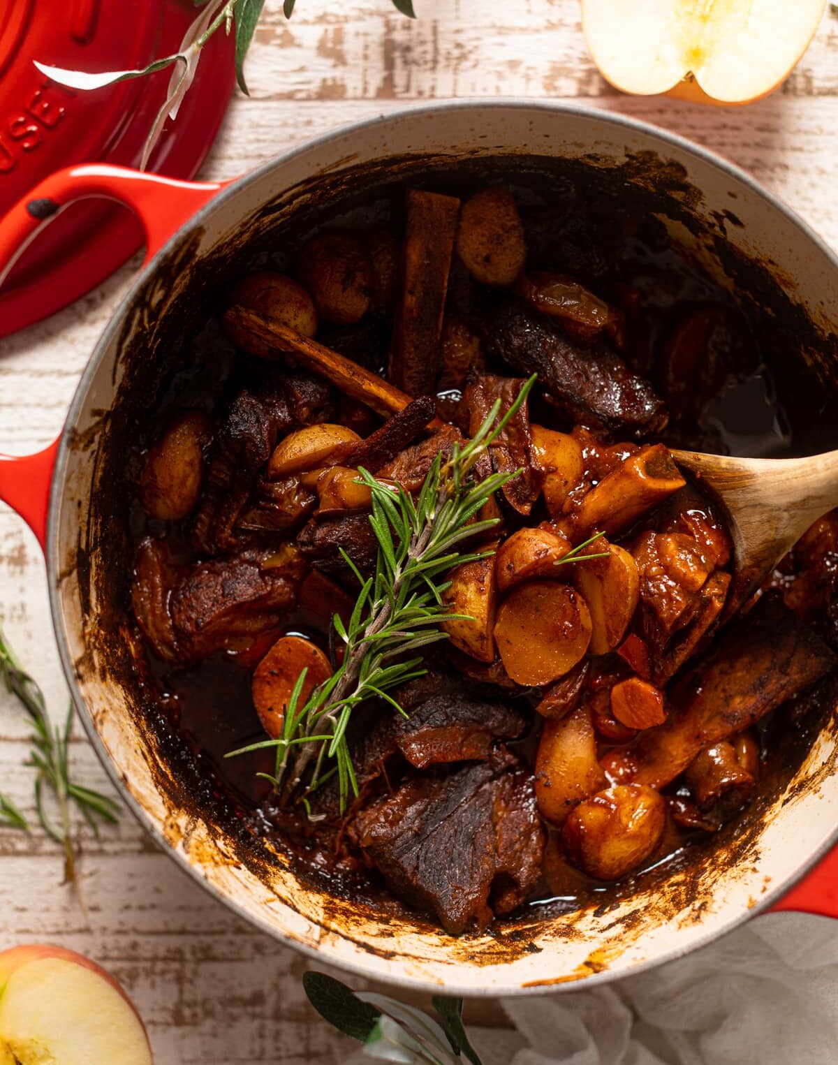 Wooden spoon stirring a pan of Braised Apple barbeque Ribs with Potatoes