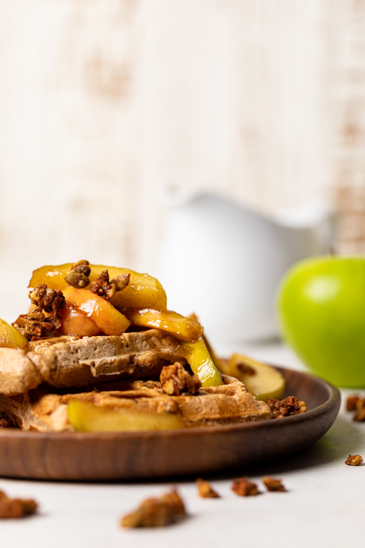 Pile of Apple Spice Cornmeal Waffles topped with caramelized apples and granola