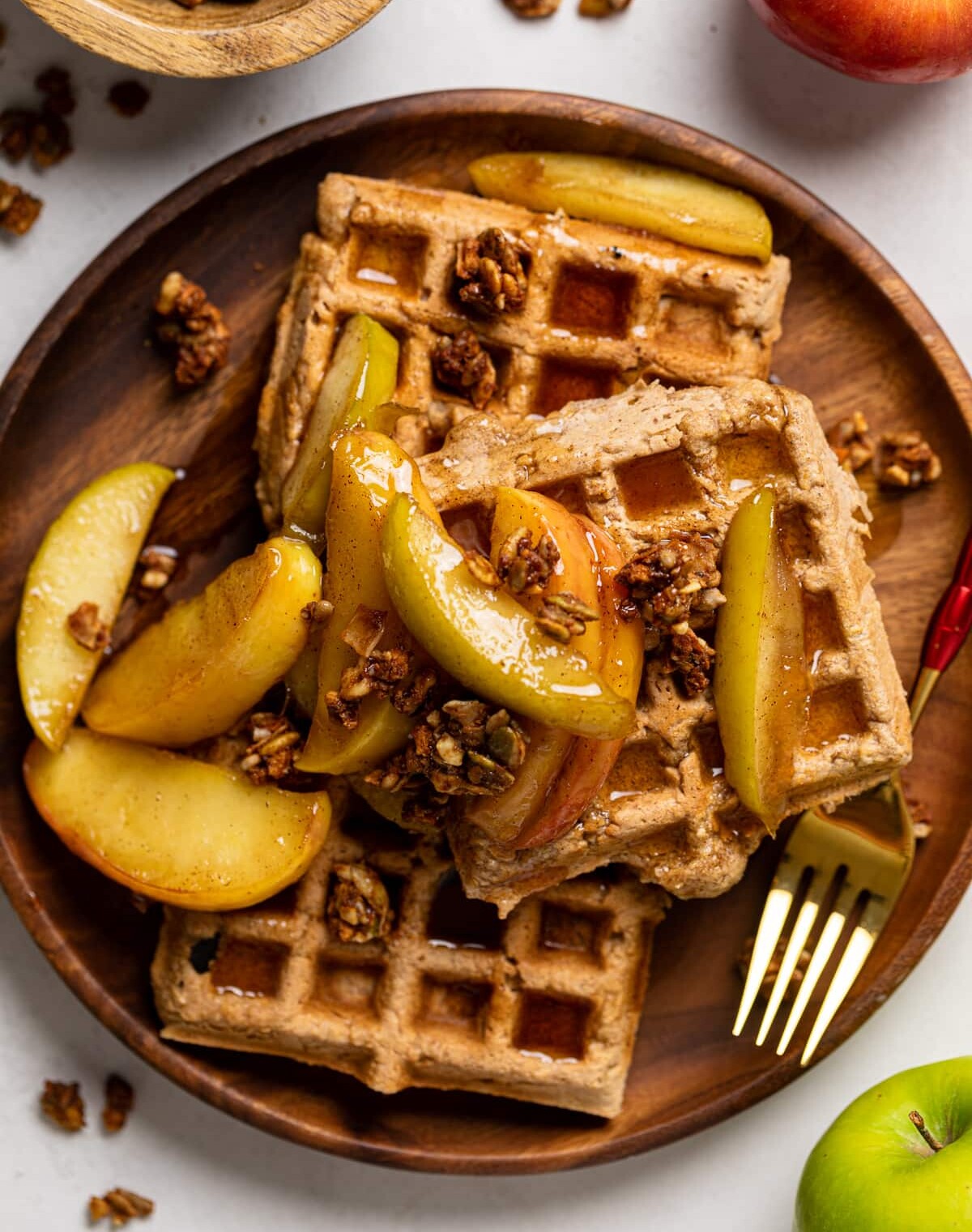Pile of Apple Spice Cornmeal Waffles topped with caramelized apples and granola