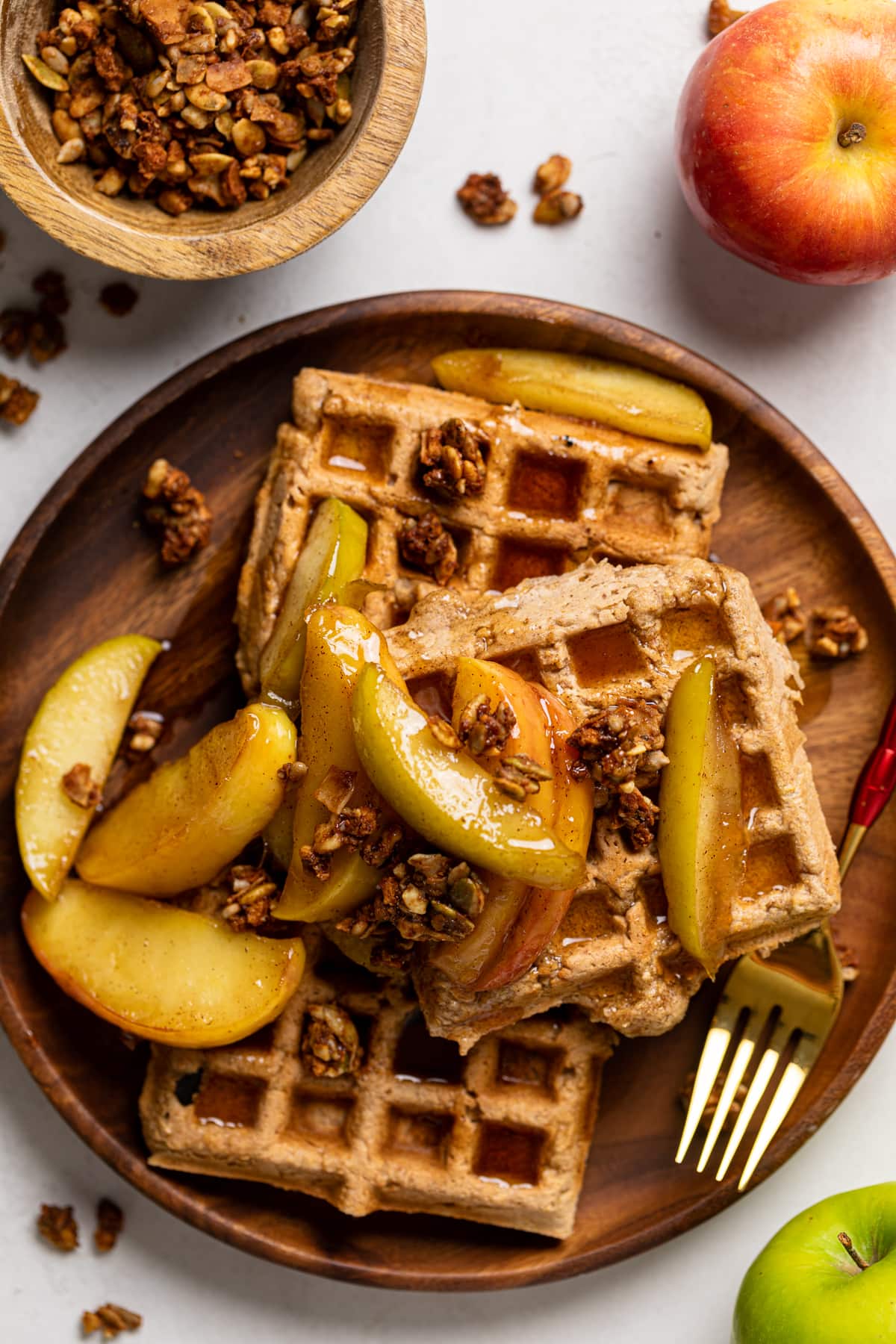 Pile of Apple Spice Cornmeal Waffles topped with caramelized apples and granola