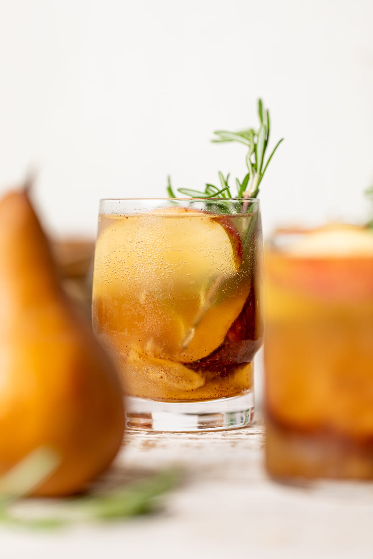 Roasted Apple Pear Mocktail in a small glass stuffed with apple slices and a sprig of rosemary