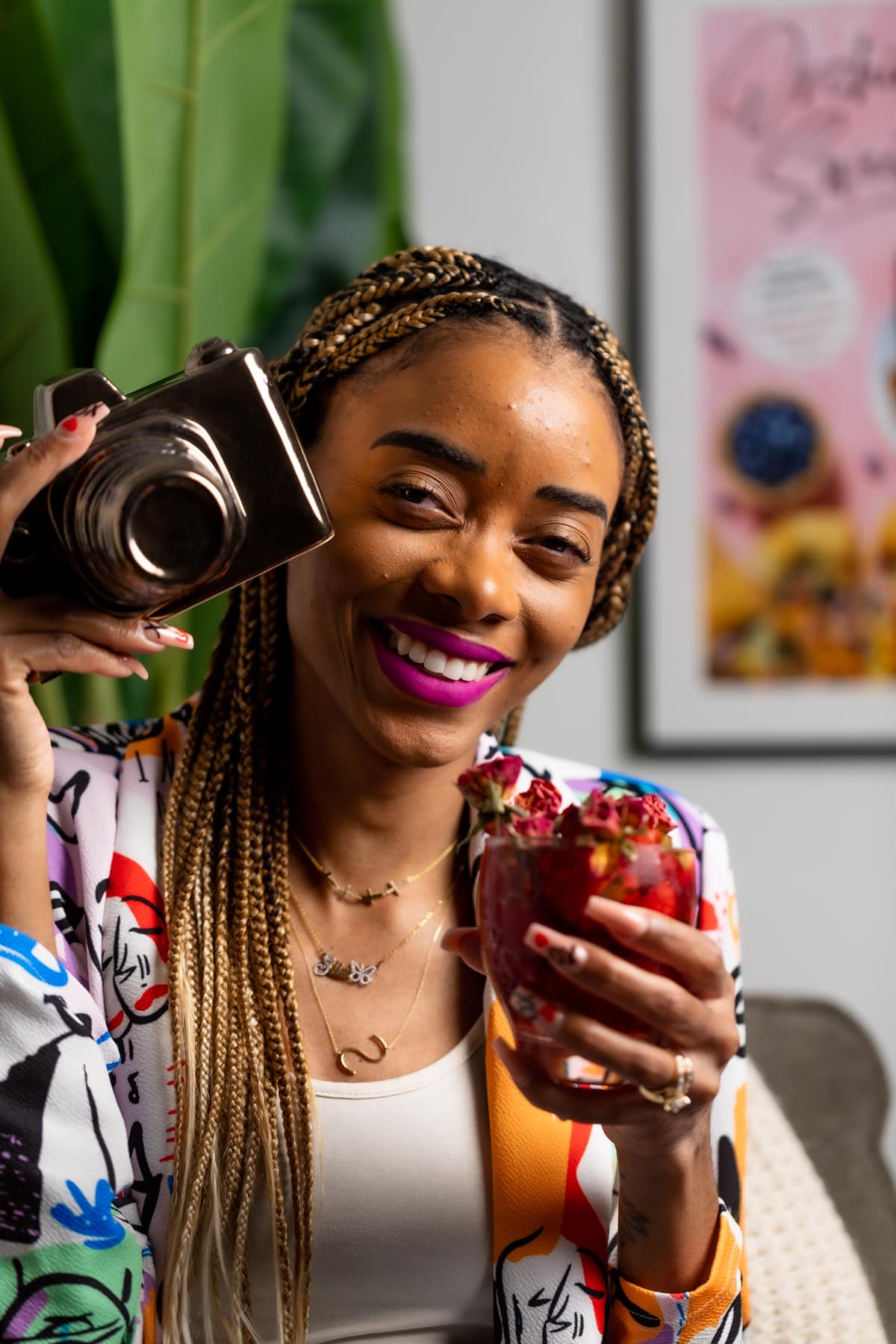Shanika smiling with a camera and a red drink in her hand