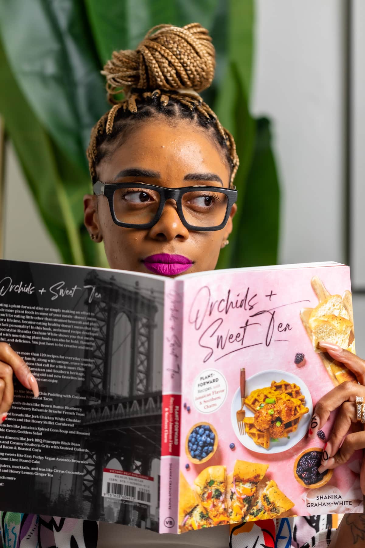 Shanika holding open the \"Orchids + Sweet Tea\" cookbook