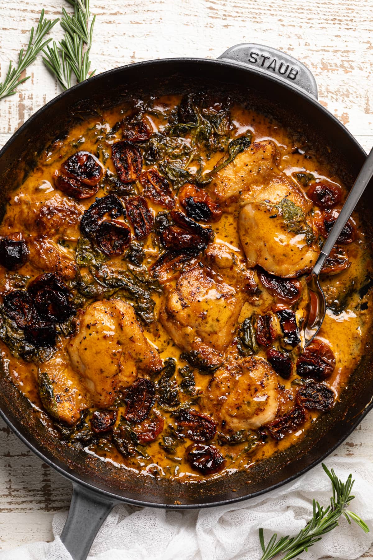 Spoon in a skillet of Creamy Tuscan Chicken and Spinach with Roasted Tomatoes